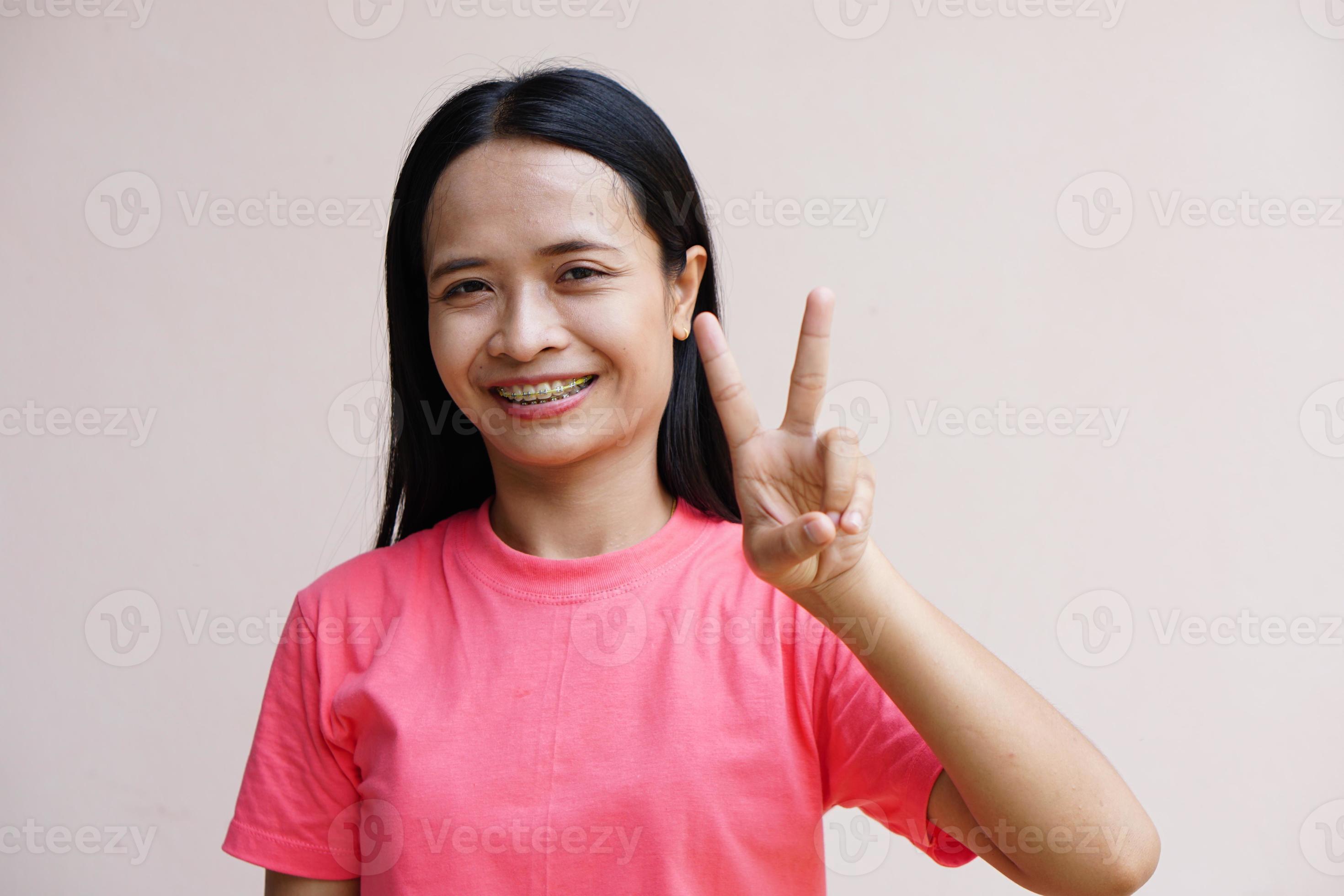 Asian woman holding up two fingers means fight 7439045 Stock Photo at