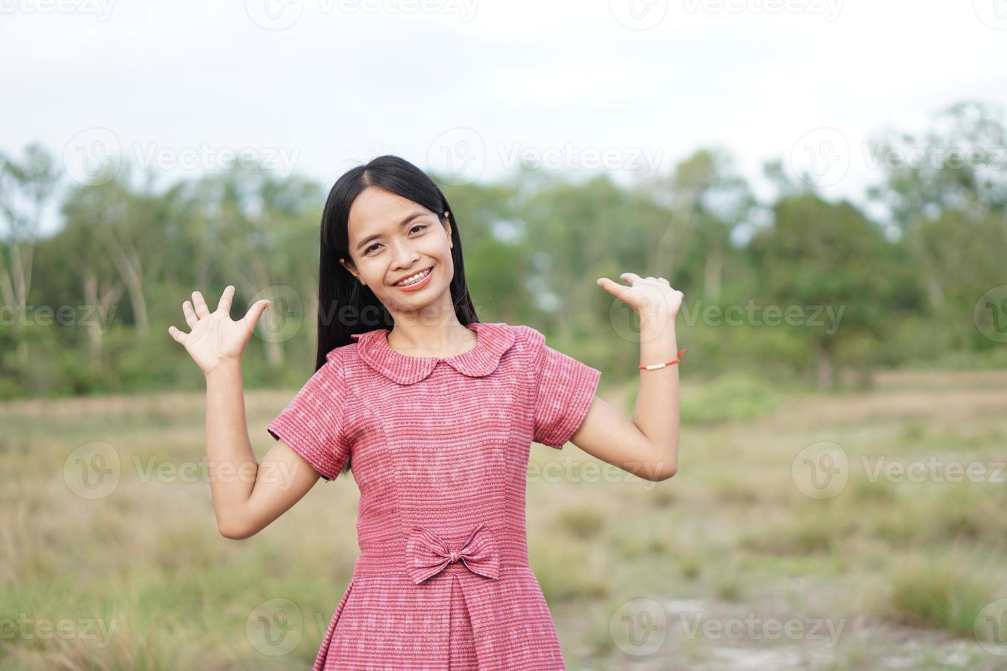 mujer asiática sonriendo alegremente levanta la mano hacia el fondo de la naturaleza del cielo foto