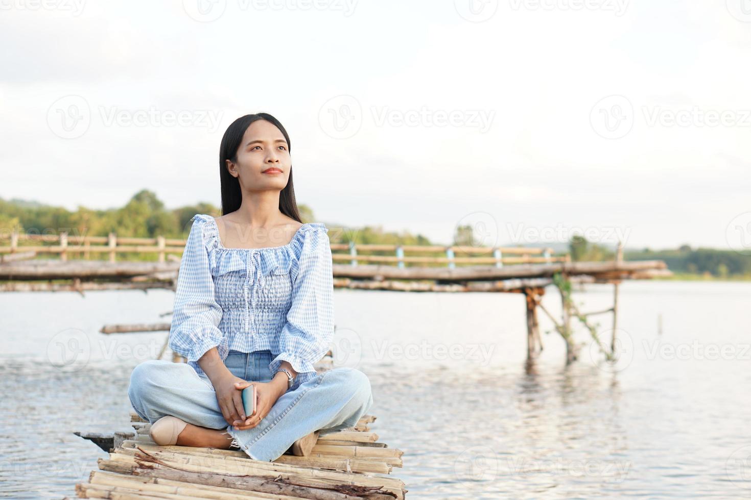 Asian female tourist sits on a bamboo bridge to reach the viewpoint. photo