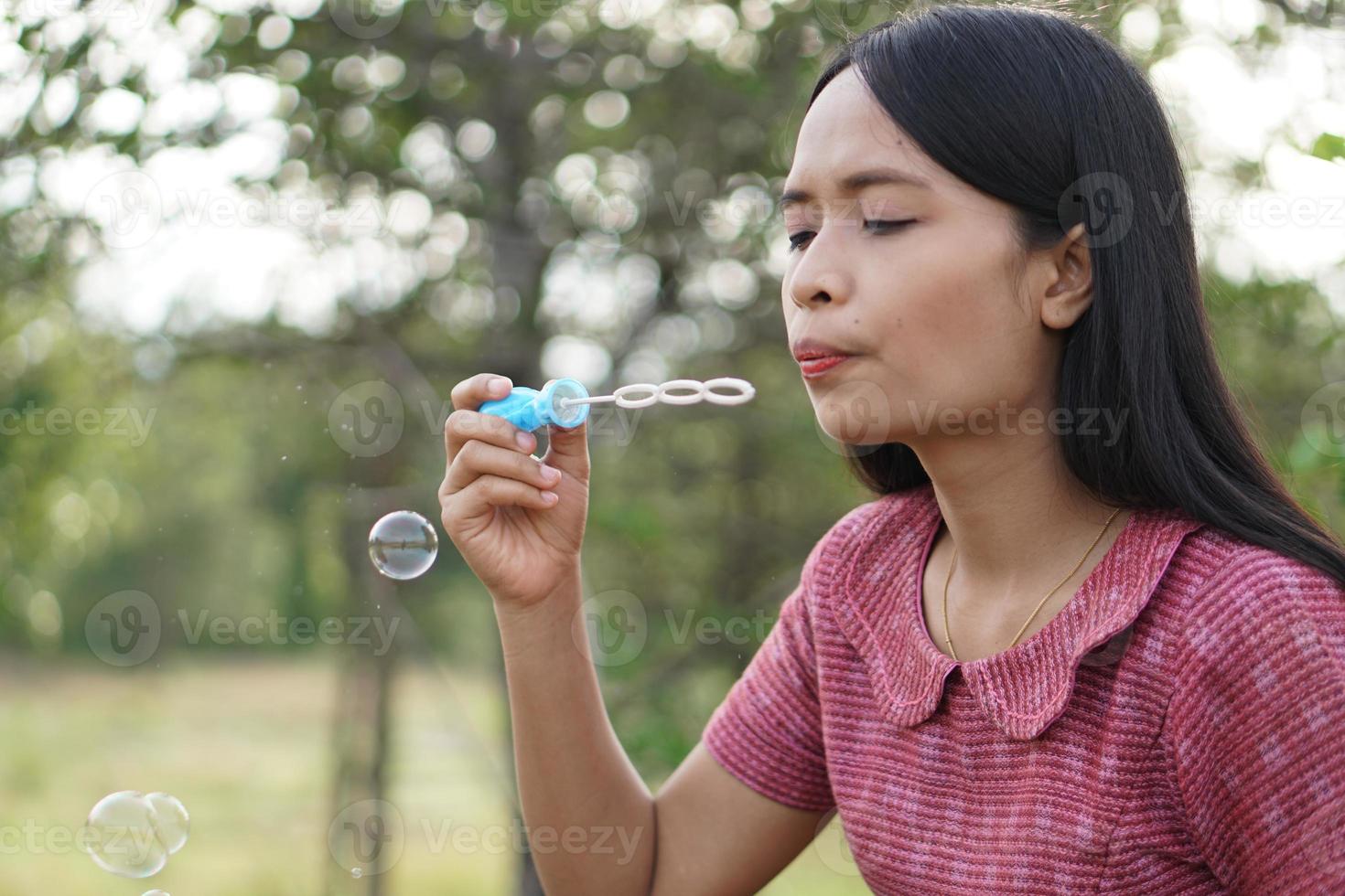 Asian woman blowing soap bubbles every green grass background photo