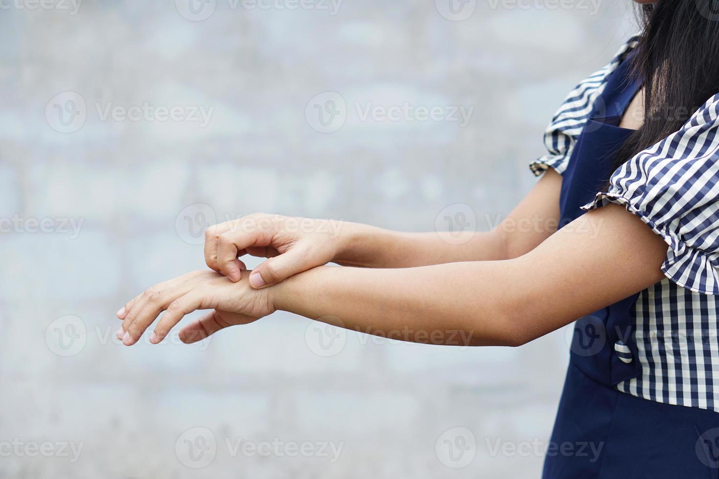 mujer rascándose el brazo por picazón en un fondo gris claro. la causa de la picazón en la piel incluye picaduras de insectos concepto de cuidado de la salud de la piel. foto