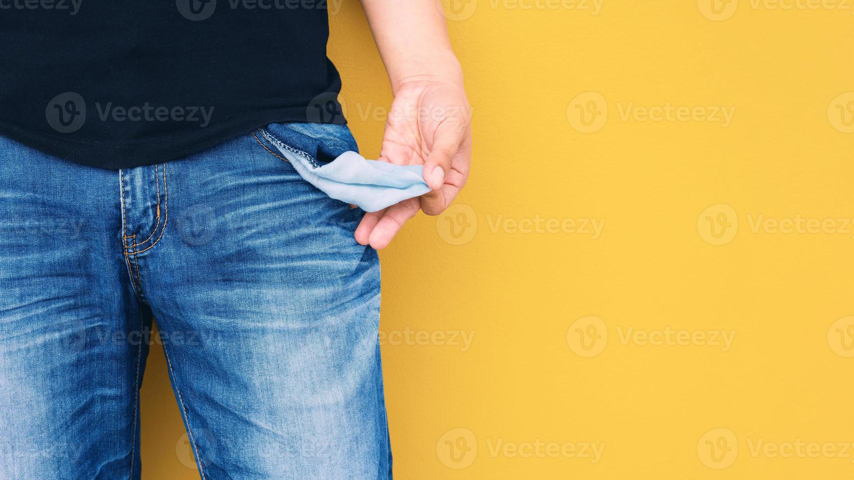 Man showing his empty pocket on yellow wall background. photo