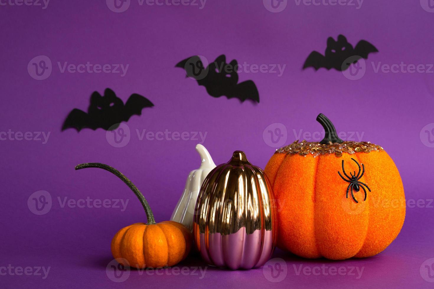 Halloween backgrounds of white, orange and gold pumpkins, spiders and black bats on a purple background with cobwebs and terrible scenery. Horror and a scary holiday with copy space photo