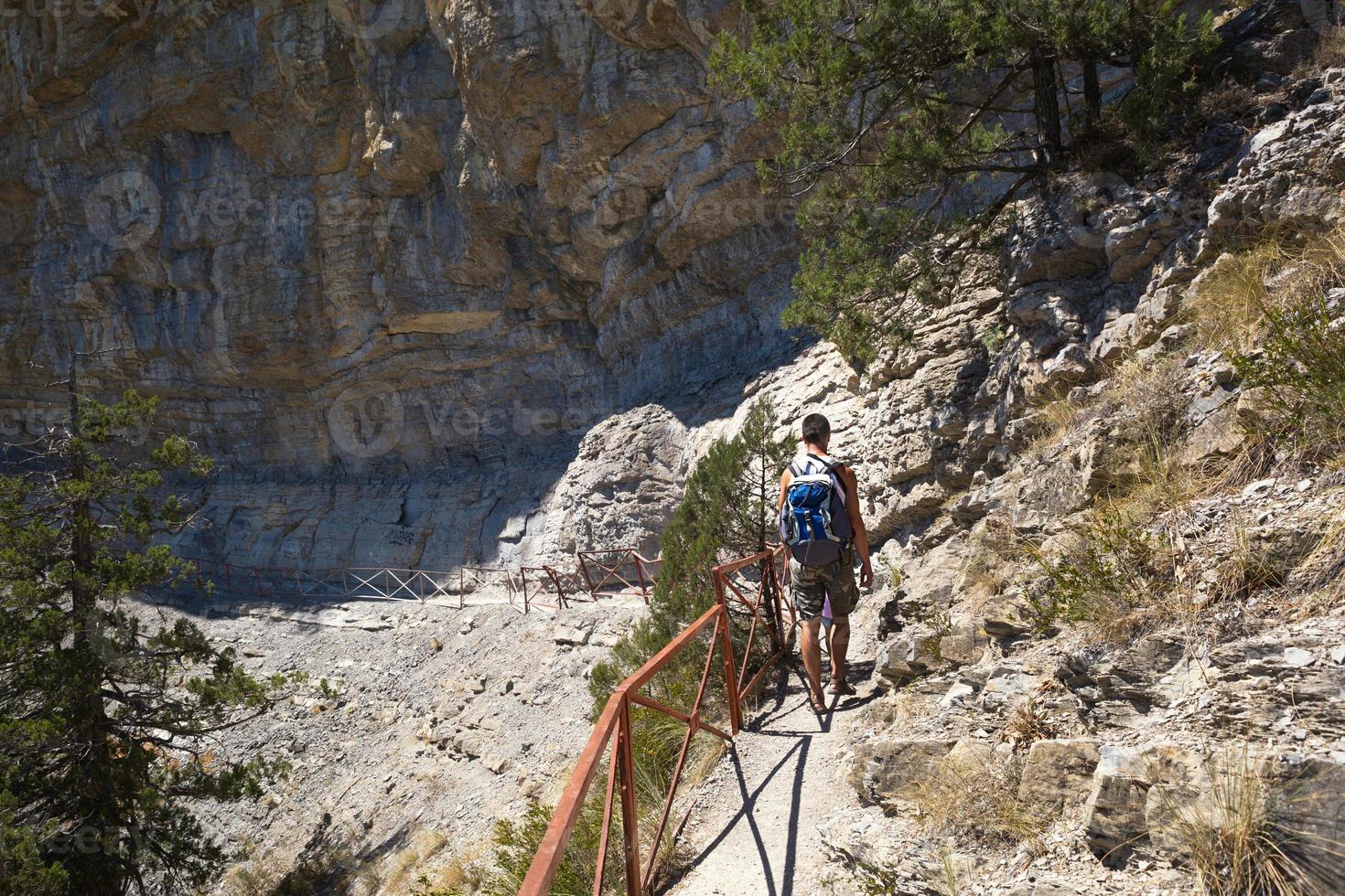 A male tourist with a backpack walks along a trail in the mountains. Travel, trekking, hiking, active lifestyle, sports tourism, health promotion, fresh air, in search of adventure. photo