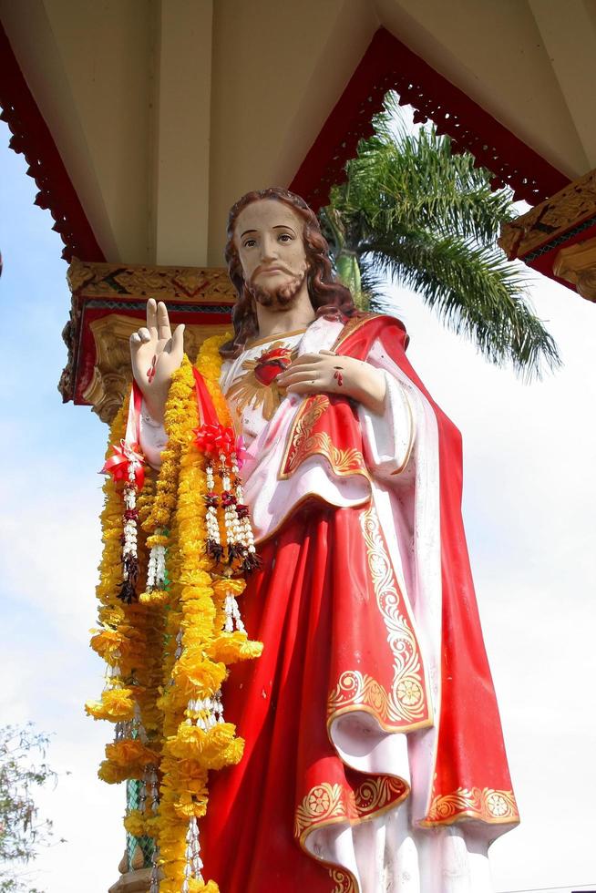 Jesus statue is standing in pavilion and Marigold garland hanging on right wrist, Thailand. photo