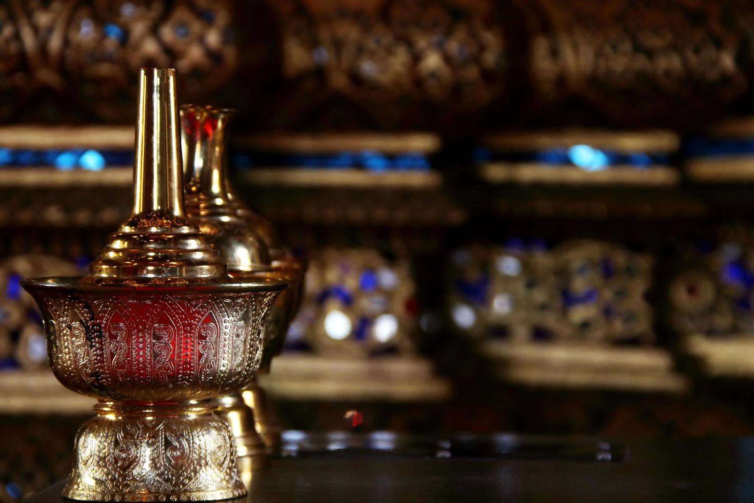 latón dorado vierta el frasco de agua ceremonial y desenfoque el fondo de arte tailandés nativo. el recipiente utilizado en buddist tailandés para verter agua de dedicación a las personas fallecidas. enfoque selectivo. foto