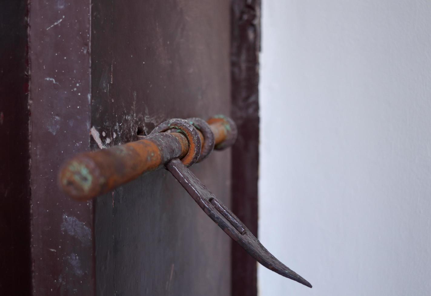 A dark brown painted door lock made from iron in ancient style, Thailand. Rusty on surface of door lock. photo