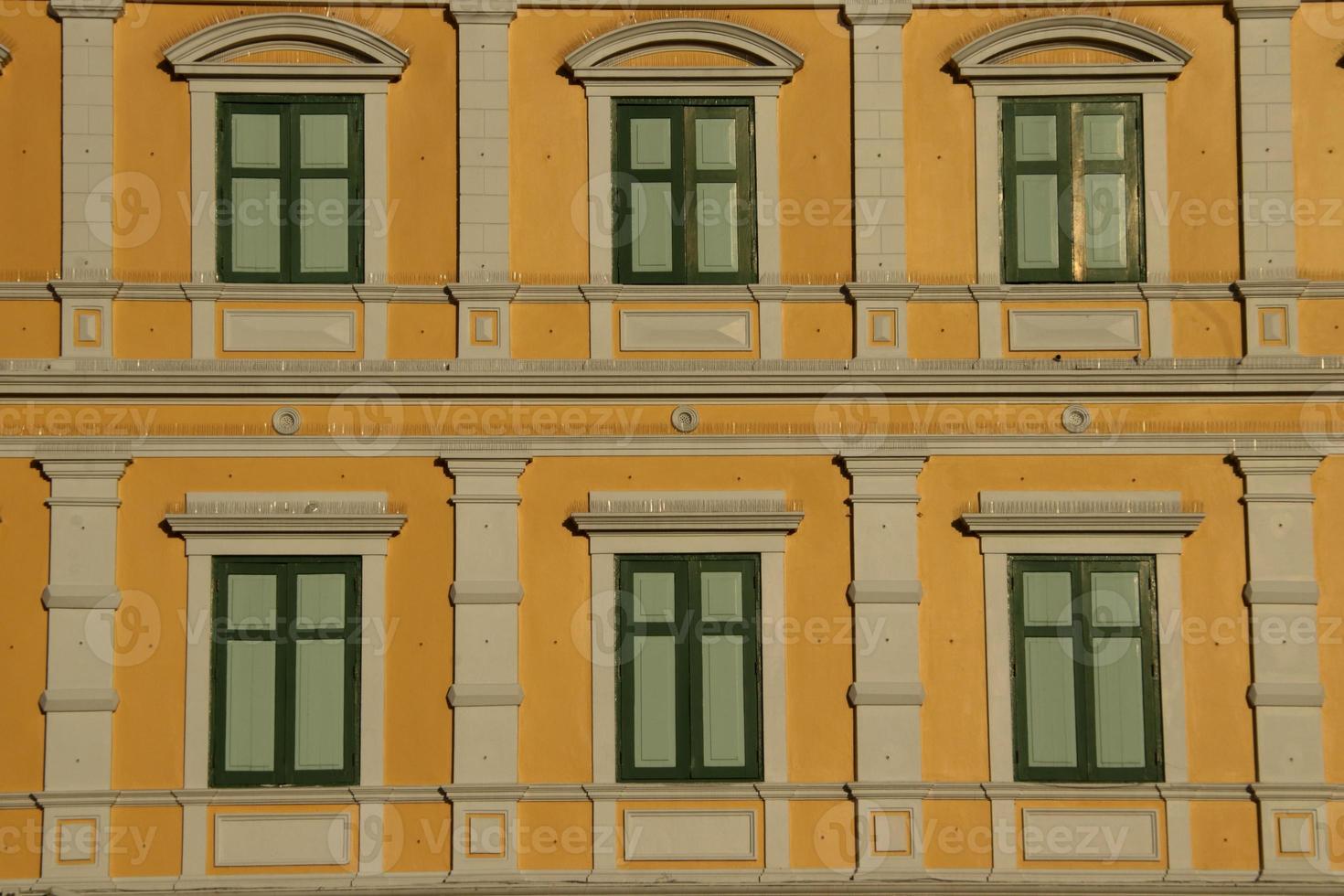 Yellow retro Europe style building and green rectangle shape windows in Bangkok, frame of windows painted dark green color, Thailand. photo