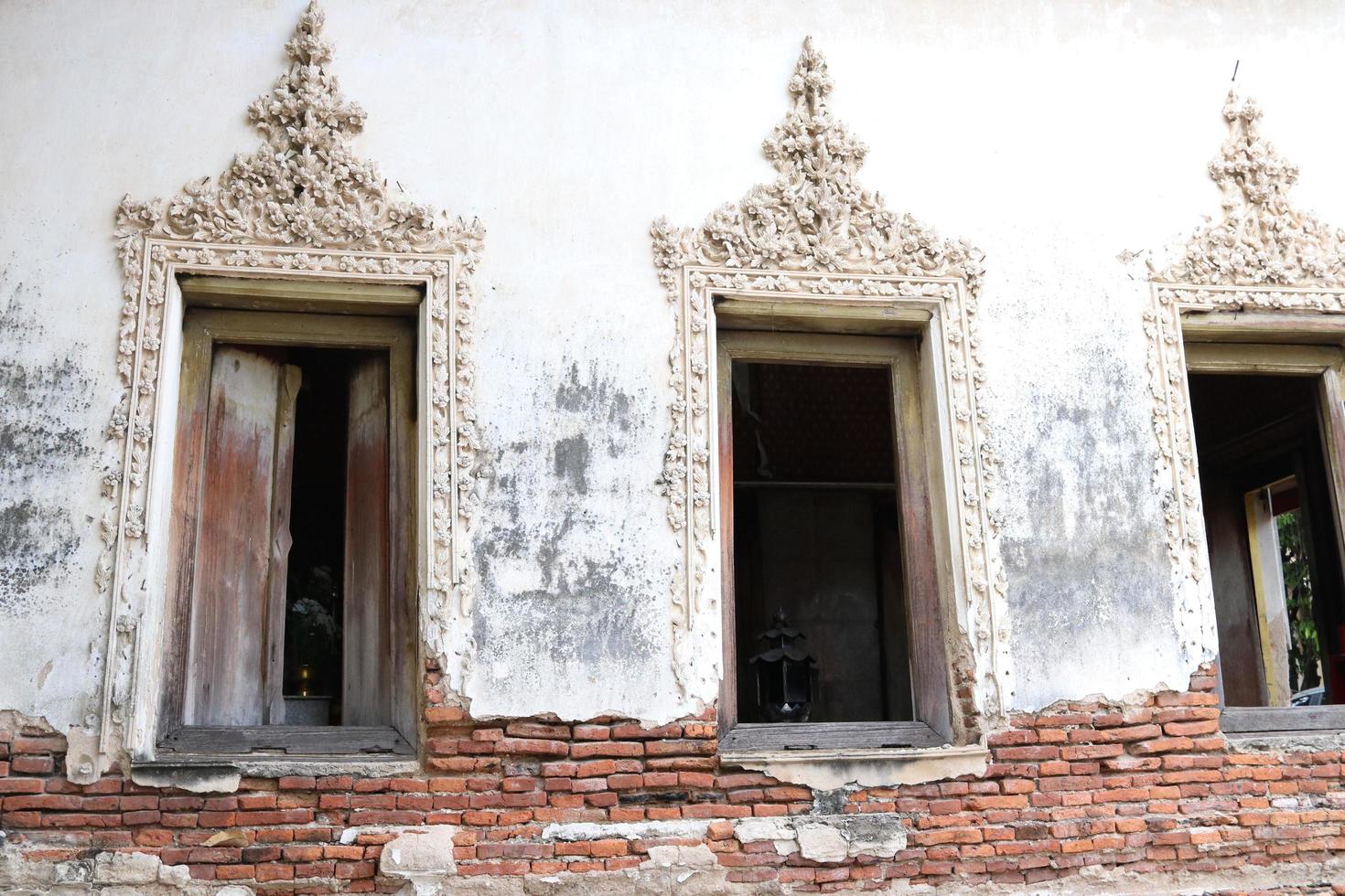 Windows of ancient native church in Bangkok, base of church is broken and open some red bricks, stucco of Thai pattern around the window, Thailand. photo