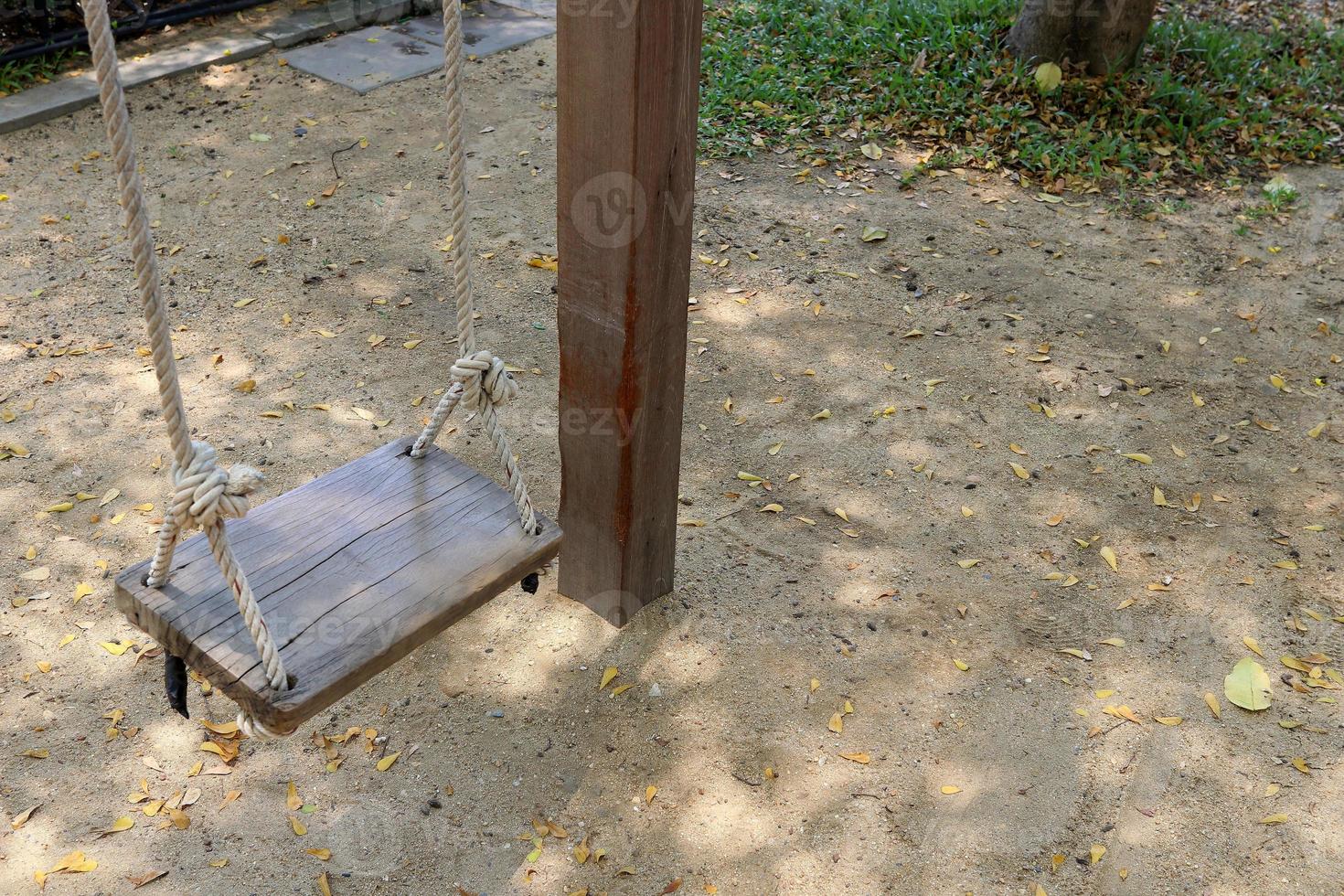 A wood swing is hanging over ground beside wood pole, Thailand. photo