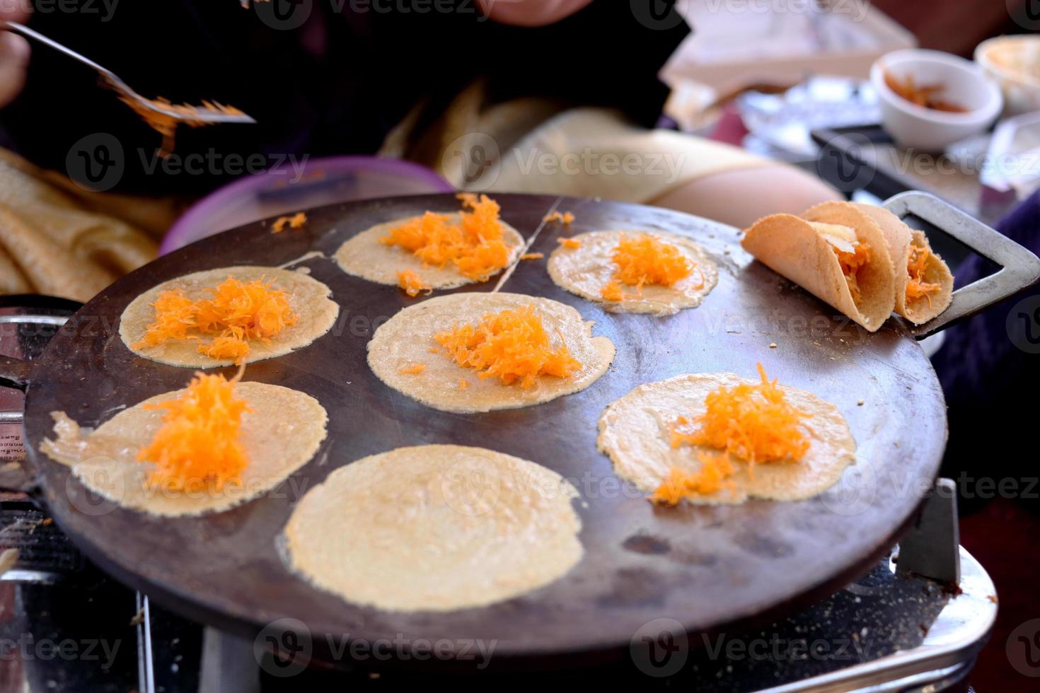 Crispy crepe base of Thai ancient crispy crepe are grilling on hot plate. Top of crispy crepe are golden threads Thai call Foy Thong, Thailand. photo