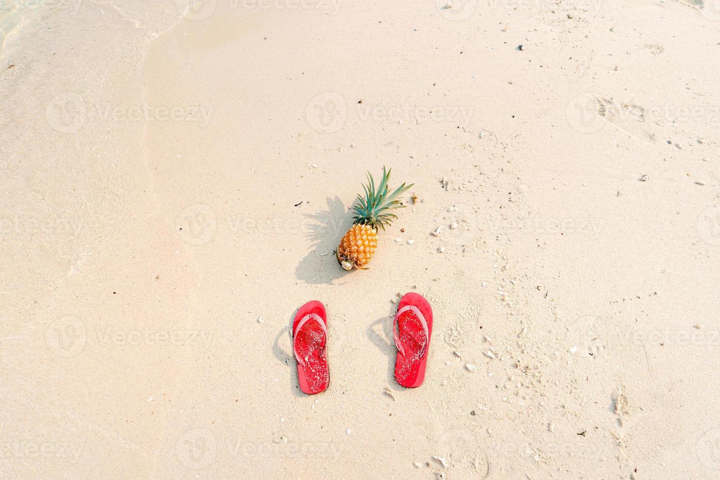 Summer beach vacation with pineapples and flip flops on the beach photo