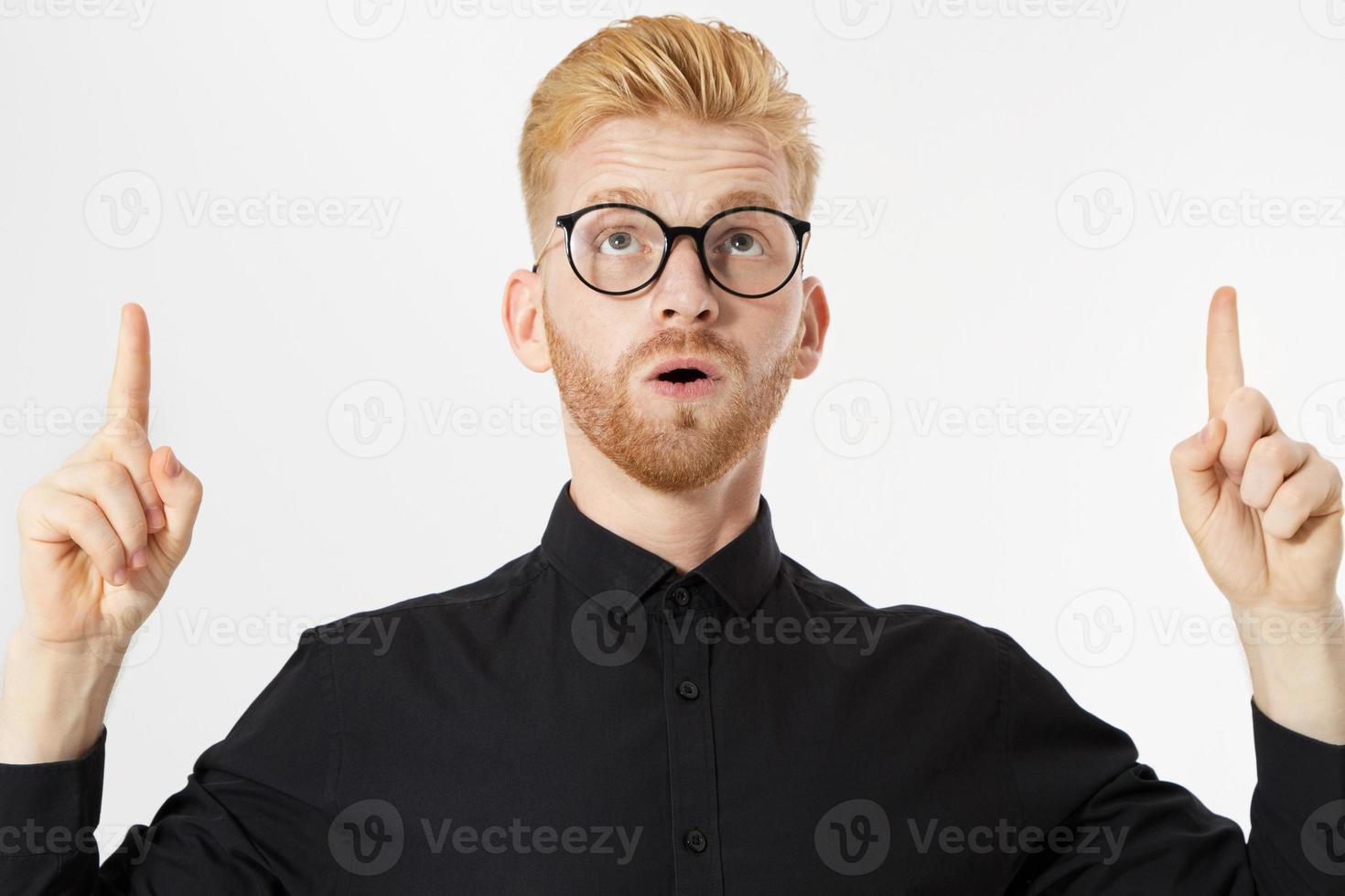 Stylish red-haired man in glasses points up photo