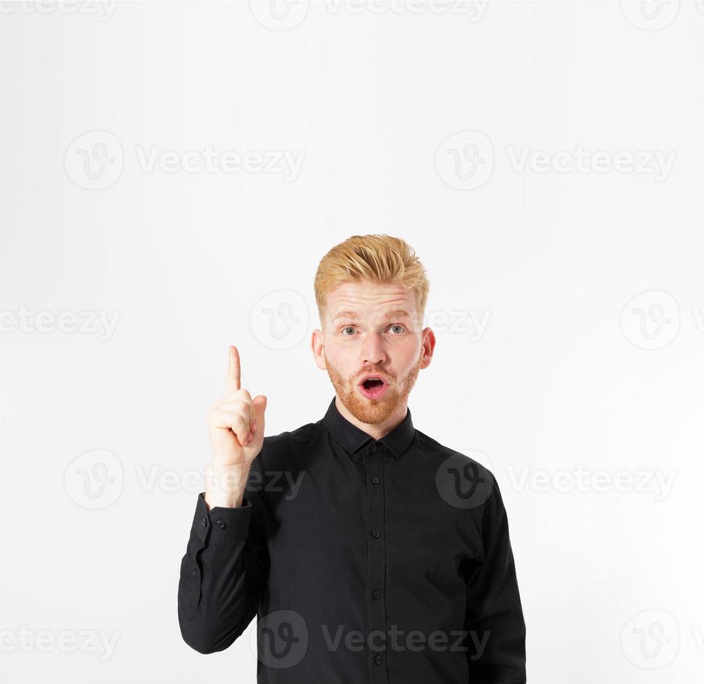 retrato de un joven pelirrojo feliz señalando con el dedo hacia arriba en el espacio vacío de la copia de fondo foto