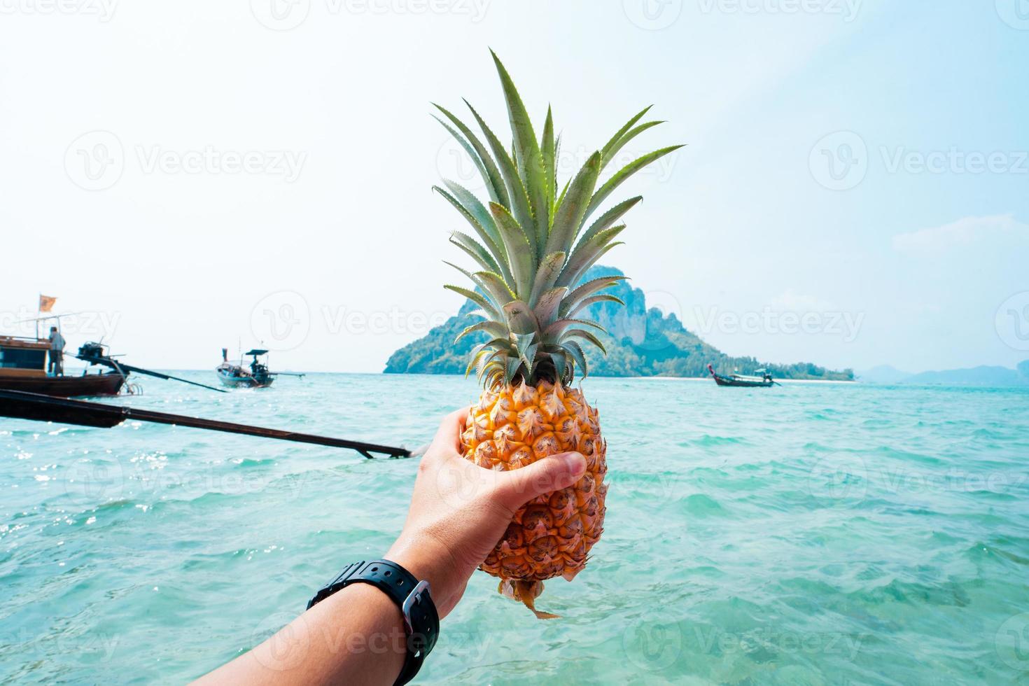 piña de verano, piña en mano en un barco en el mar foto