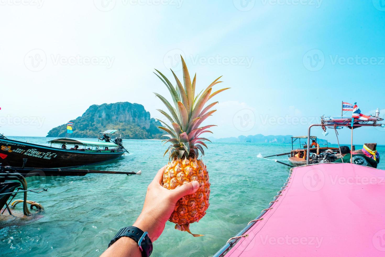 piña de verano, piña en mano en un barco en el mar foto