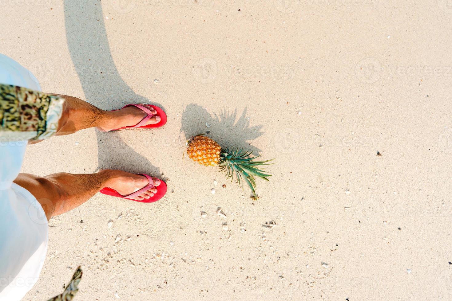 Summer beach vacation with pineapples and flip flops on the beach photo