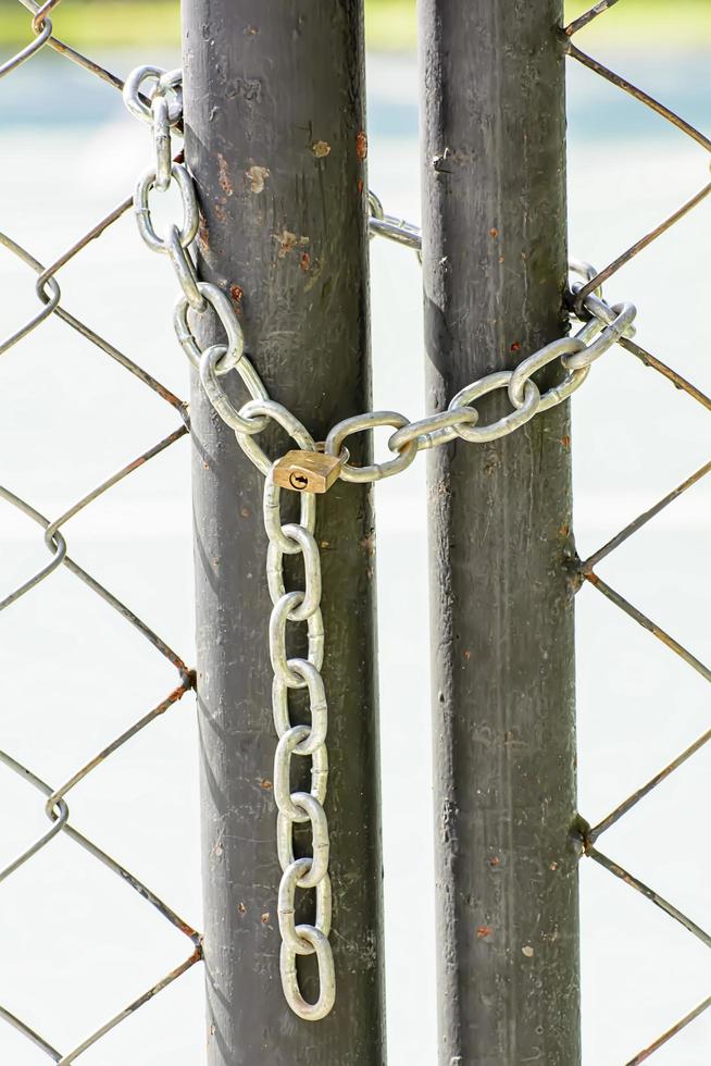 A lock and chain on Metal Fence that links of a gate. photo