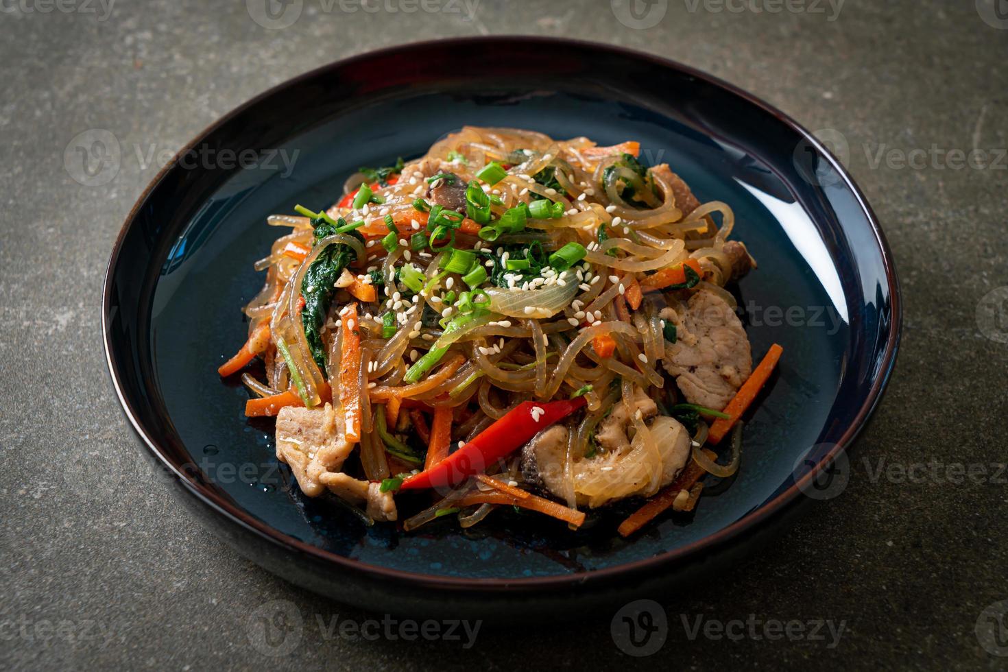 japchae or stir-fried Korean vermicelli noodles with vegetables and pork topped with white sesame photo