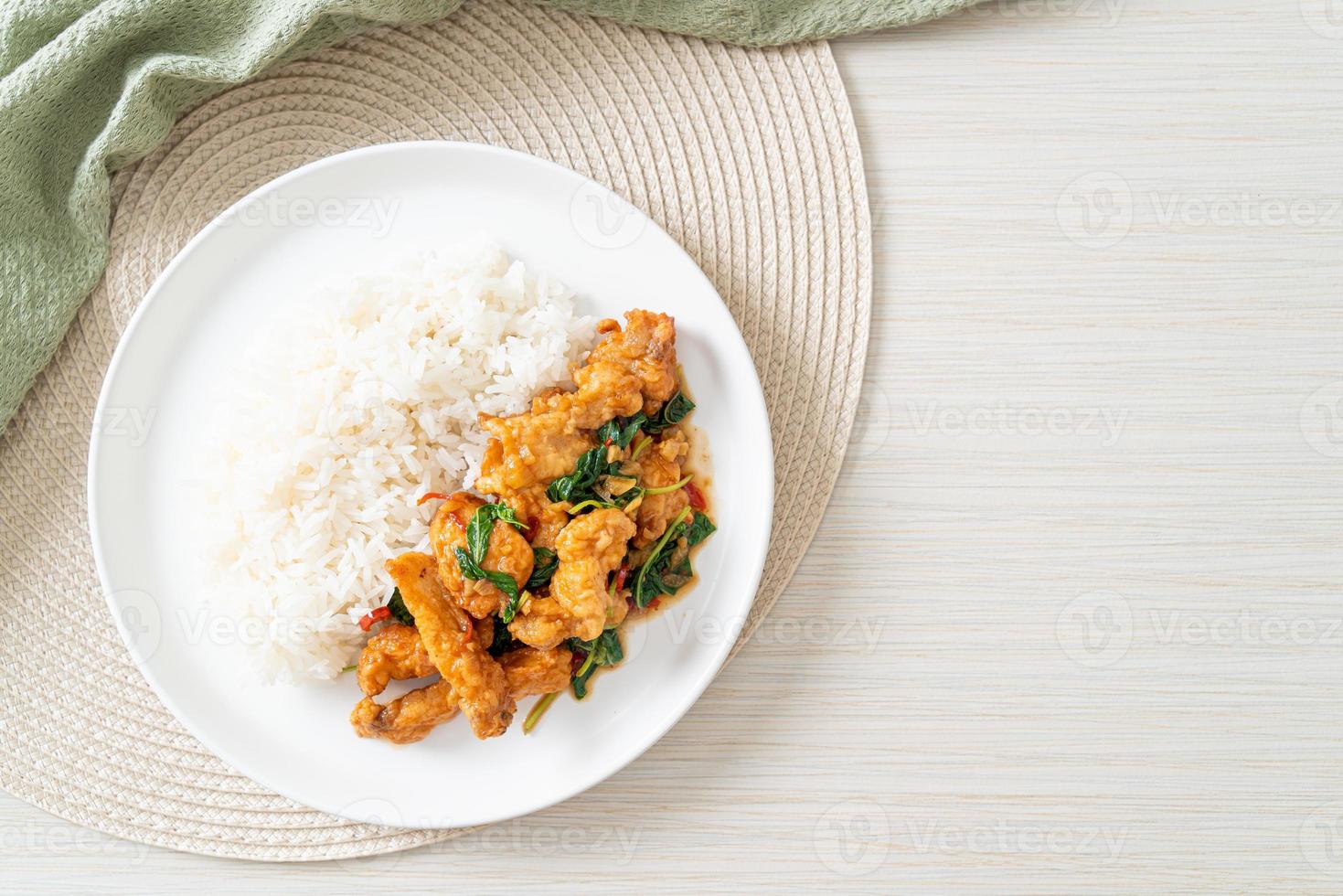 stir-fried fried fish with basil and chili in thai style topped on rice photo