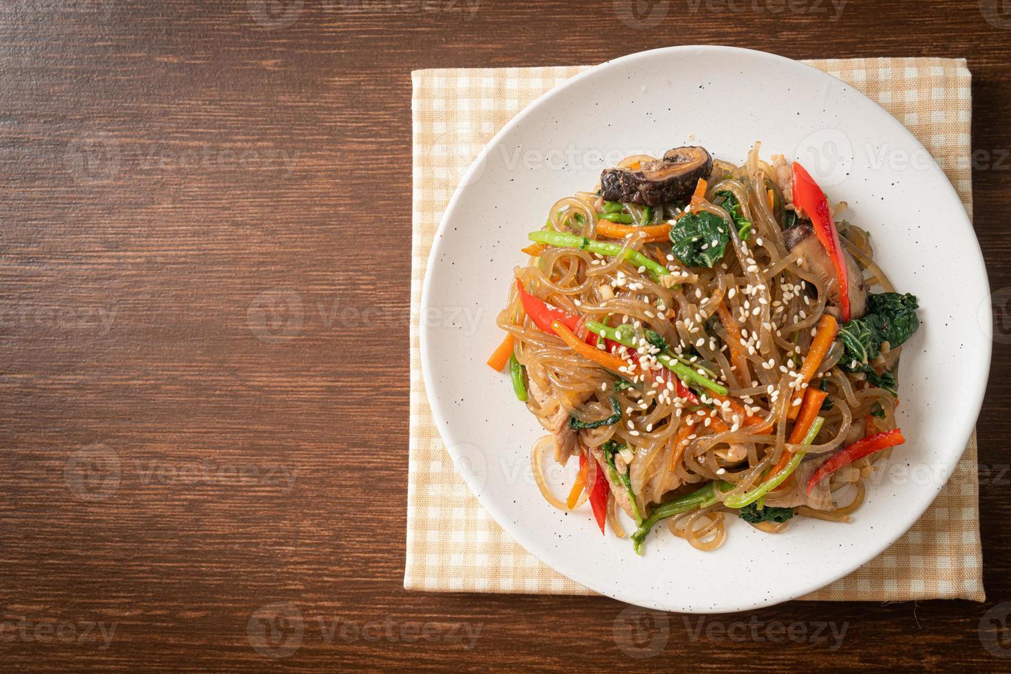 japchae or stir-fried Korean vermicelli noodles with vegetables and pork topped with white sesame photo