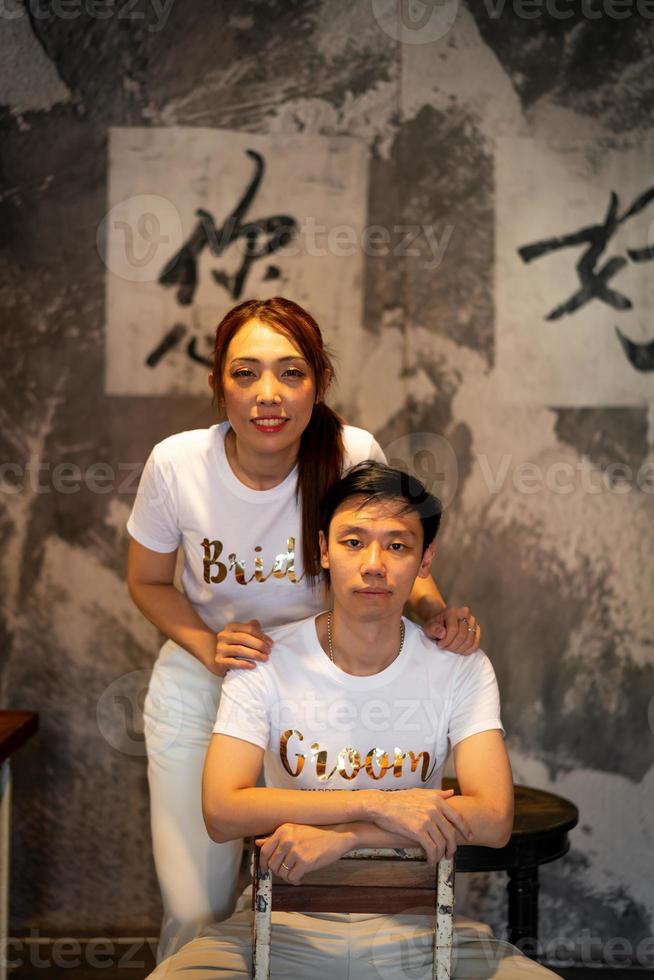 Happy young Asian couple in bride and groom t-shirt photo