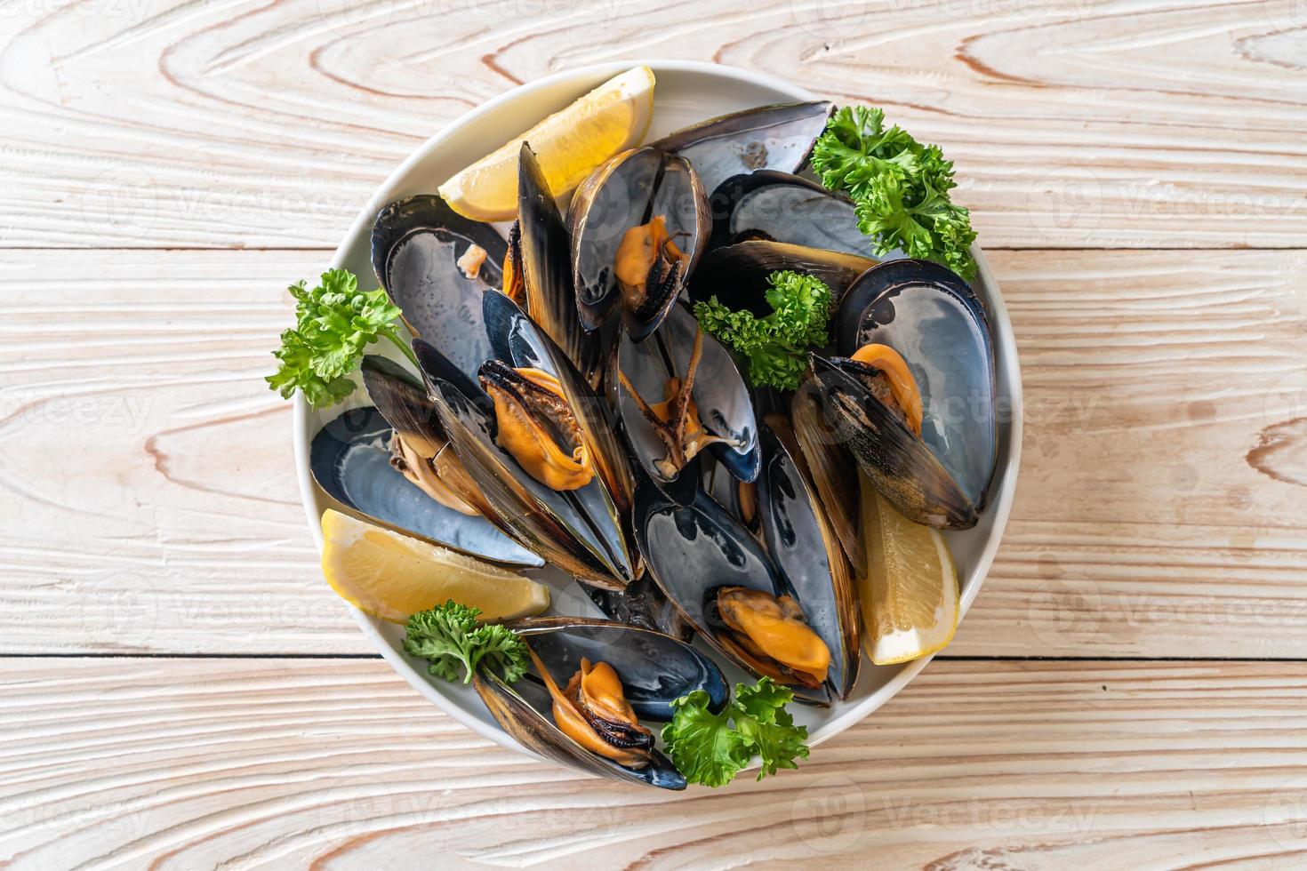 mejillones con hierbas en un bol con limón foto