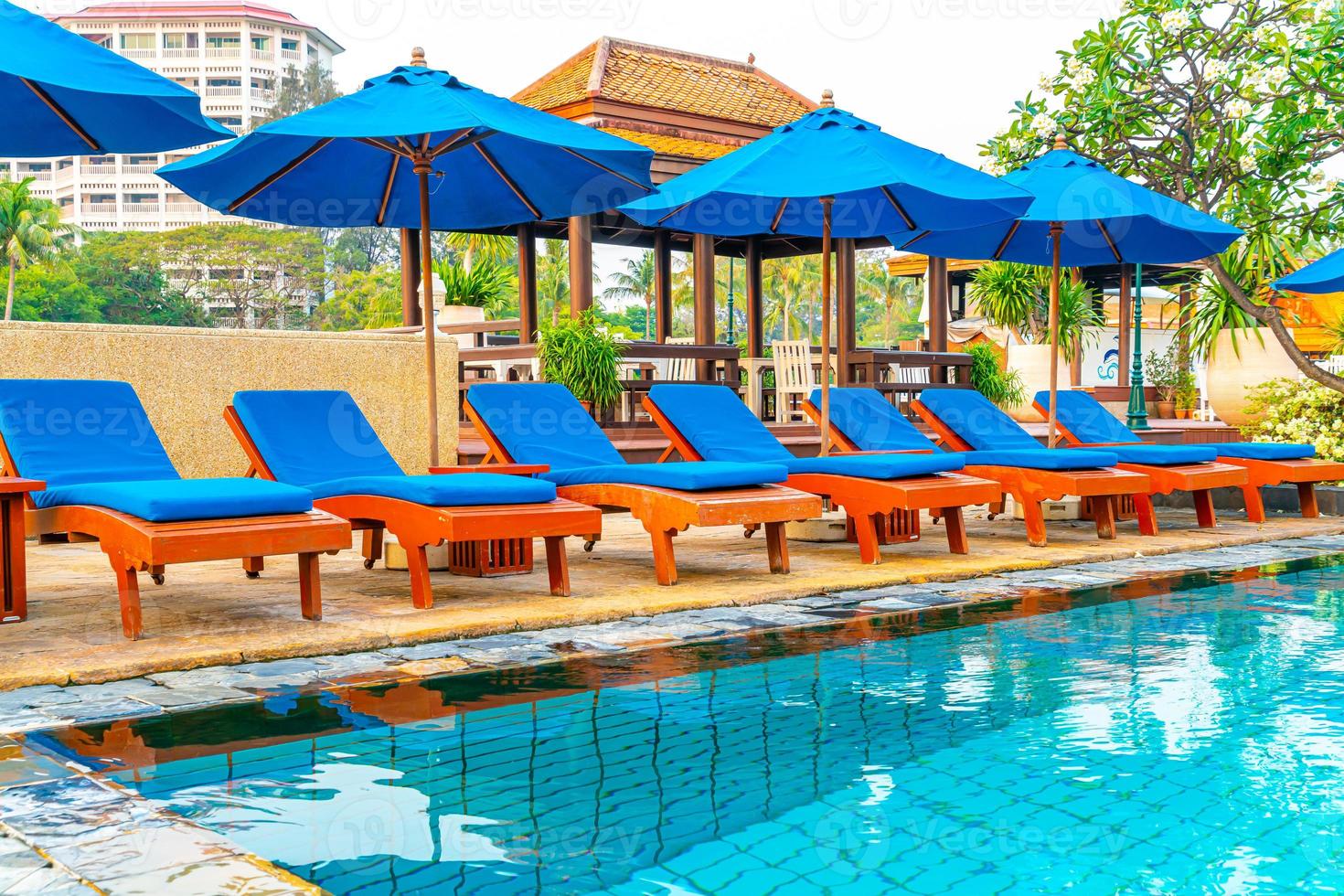 Beautiful umbrella and chair around swimming pool in hotel and resort photo