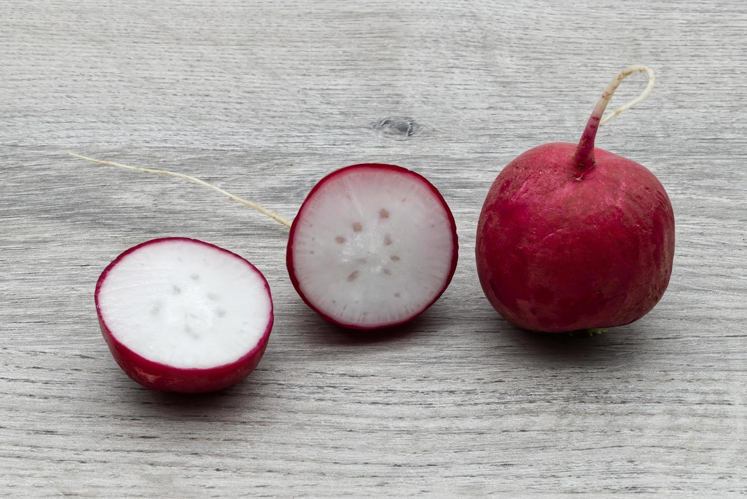 Rodajas de rábano rojo fresco aislado sobre fondo de madera foto