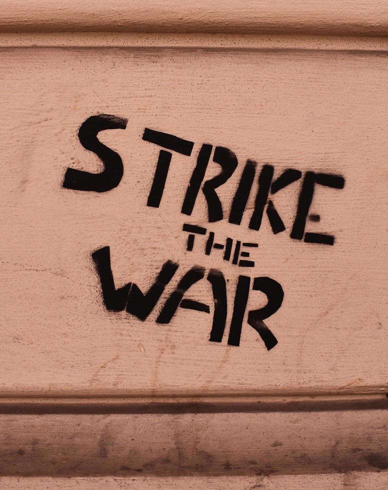 Strike the war, isolated black text written on the wall. photo