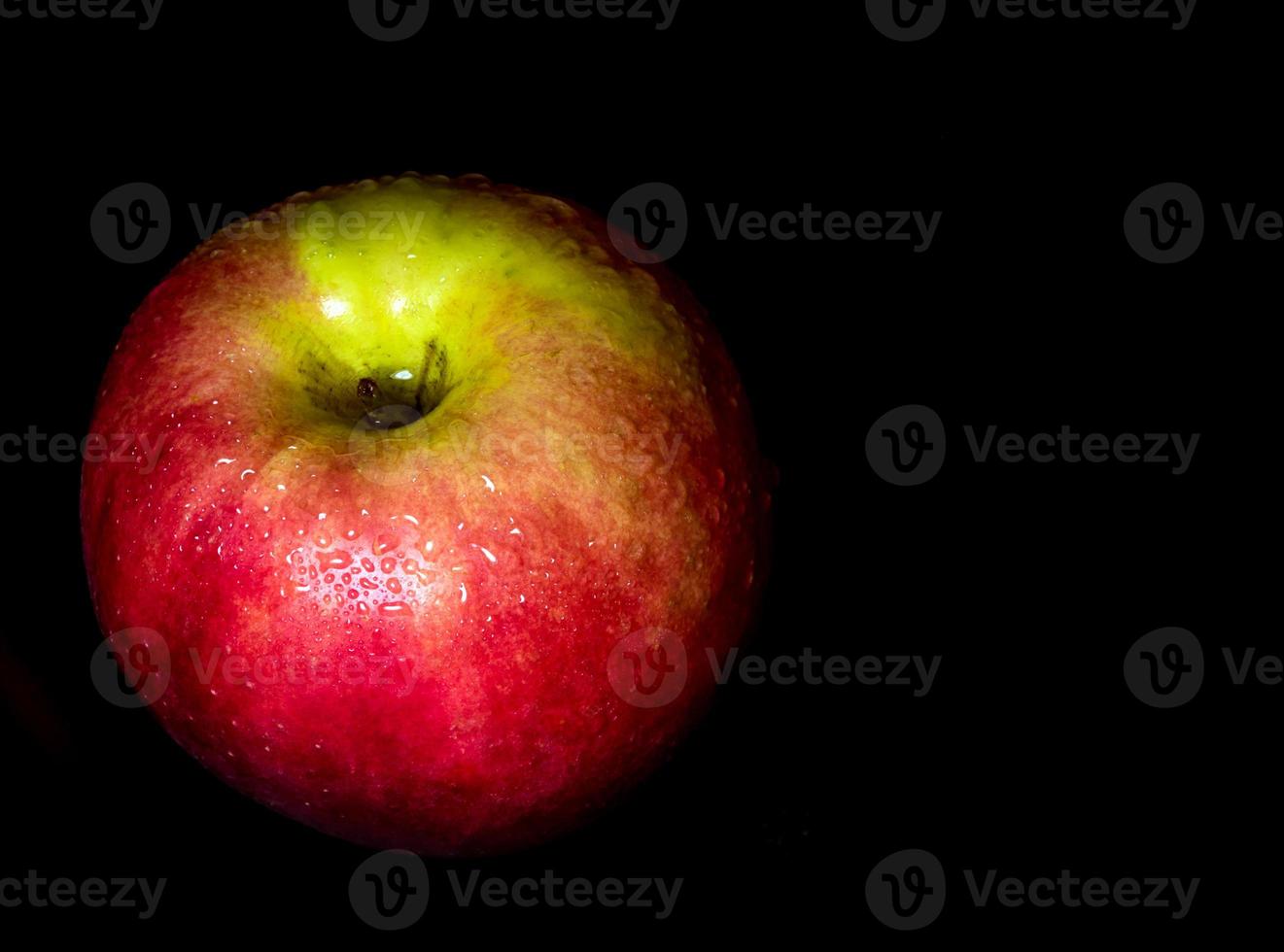 Water droplet on glossy surface of red apple on black background photo