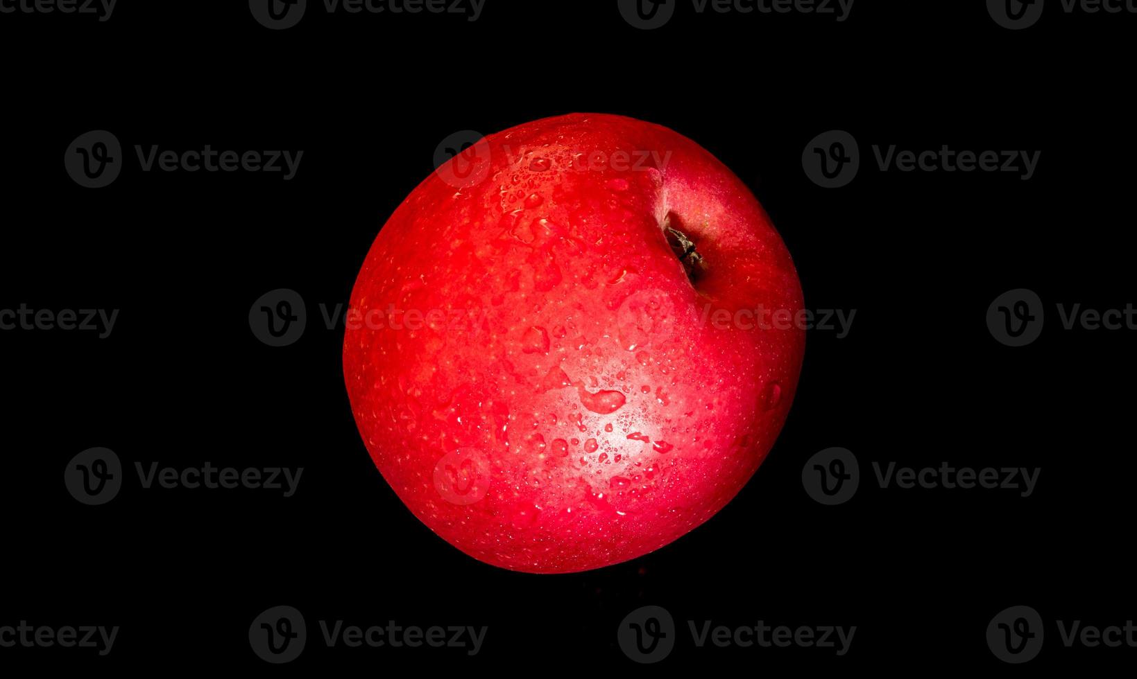 Water droplet on glossy surface of red apple on black background photo