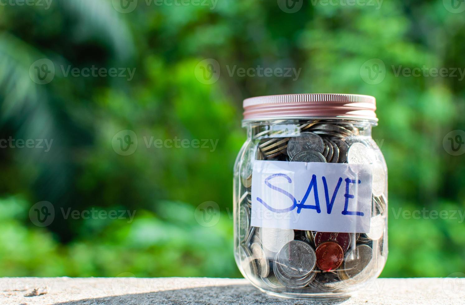 Blurred background, Coins and text SAVE in a glass jar placed on a wooden table. Concept of saving money for investment and emergency situations Or during the coronavirus COVID-19 outbreak. Close up photo