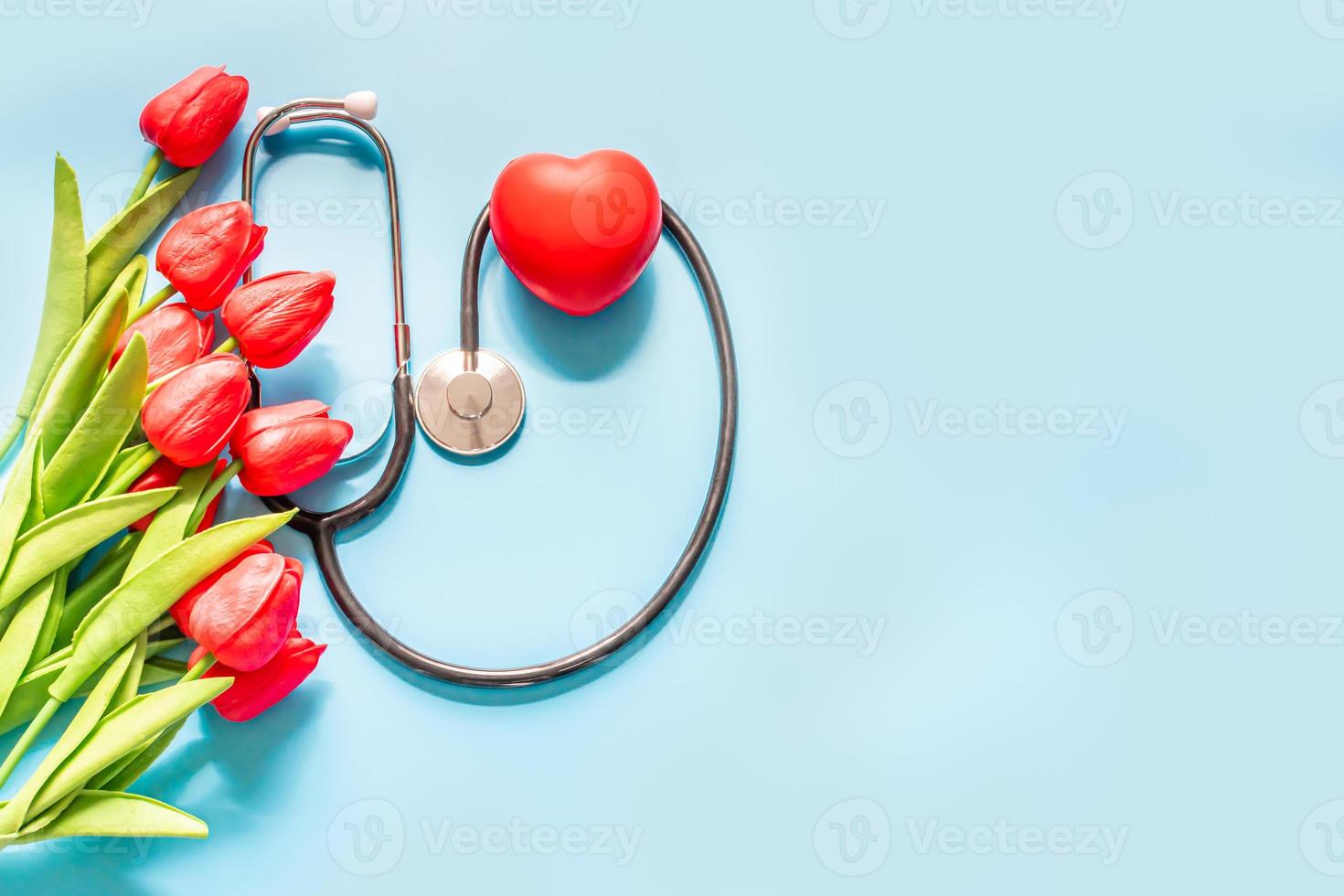 estetoscopio, tulipanes, sobre fondo azul. fondo de saludo. feliz dia de la enfermera. dia de la salud día nacional del médico. vista superior, copie el espacio a la derecha. gracias doctores y enfermeras. enfoque selectivo foto