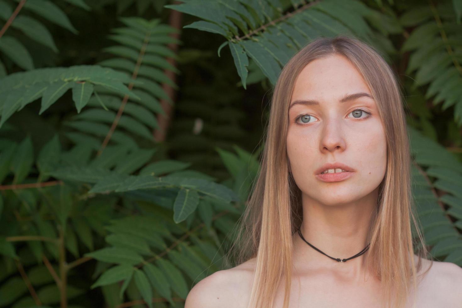 retrato de una bella joven con hojas verdes, una bella dama rubia con arbustos de primavera foto