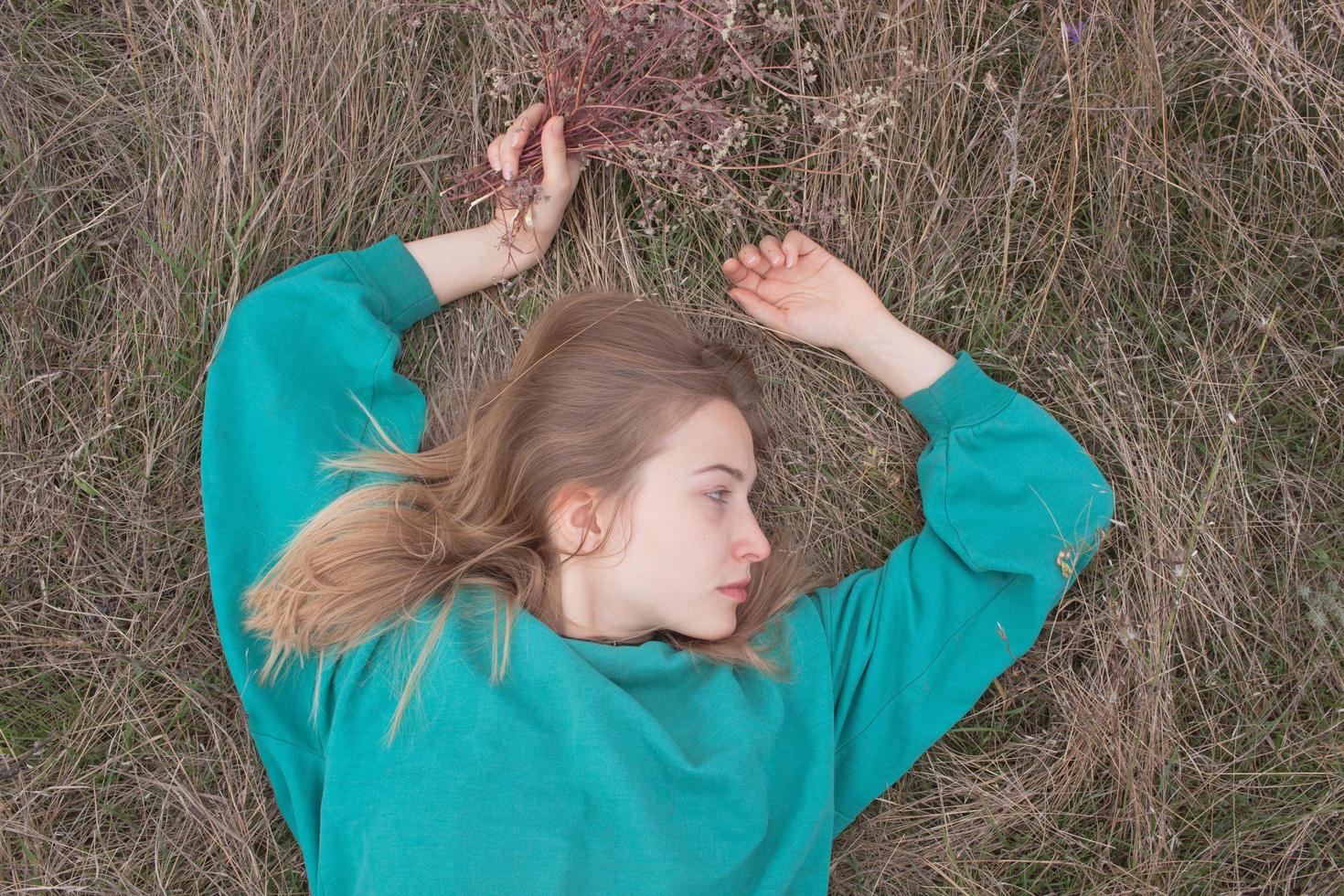 mujer joven en los campos, retrato de una mujer hermosa relajándose en la hierba seca foto