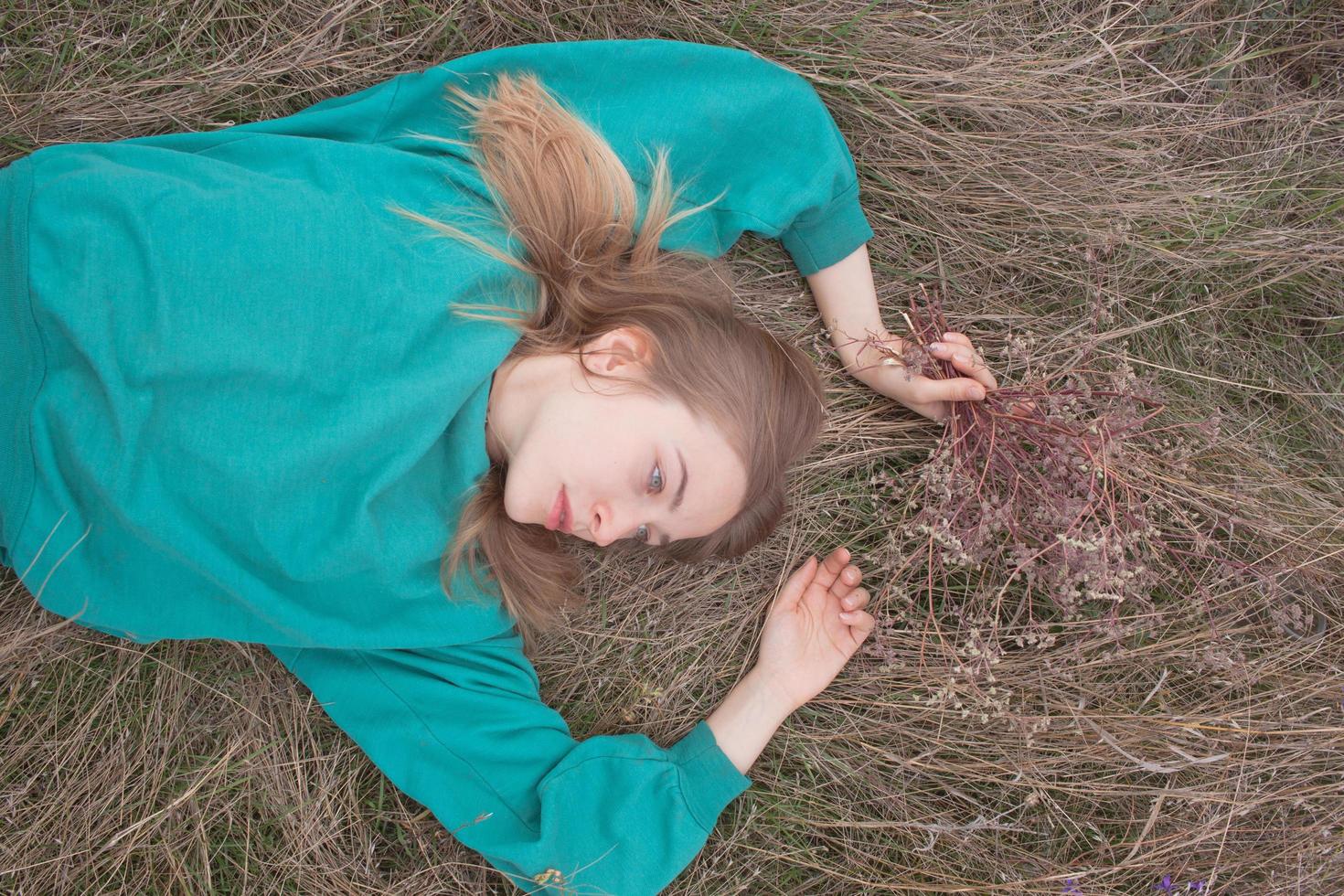 mujer joven en los campos, retrato de una mujer hermosa relajándose en la hierba seca foto