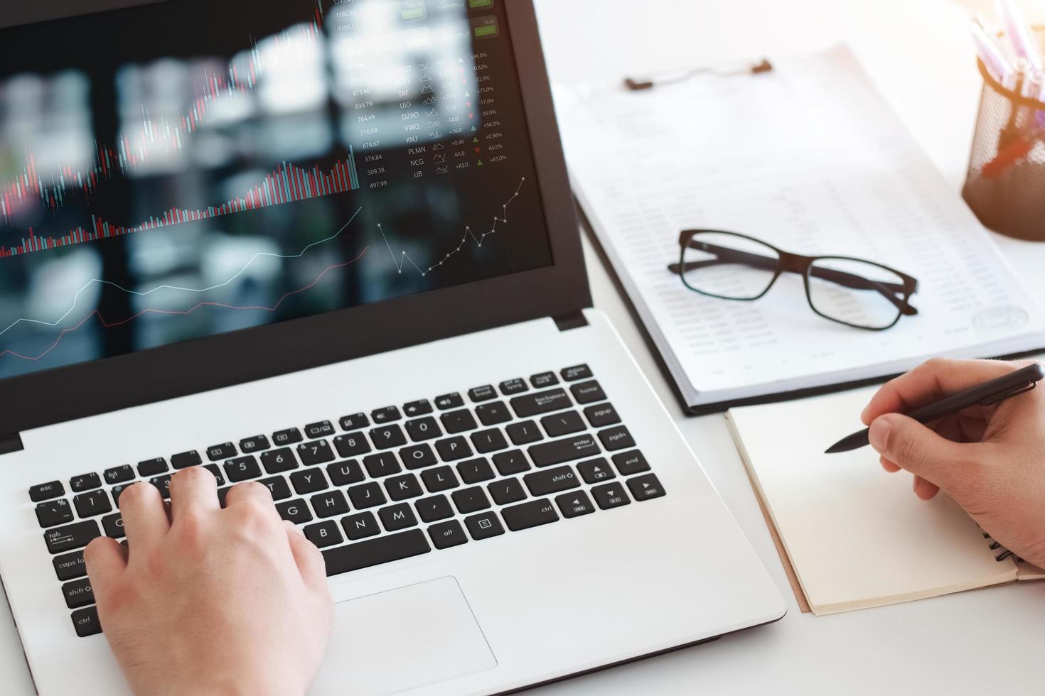 los hombres de negocios trabajan con inversiones bursátiles usando computadoras portátiles para analizar datos comerciales. computadora de escritorio con gráfico bursátil en pantalla. mercado de valores financiero. analizando datos en el fondo de la oficina. foto