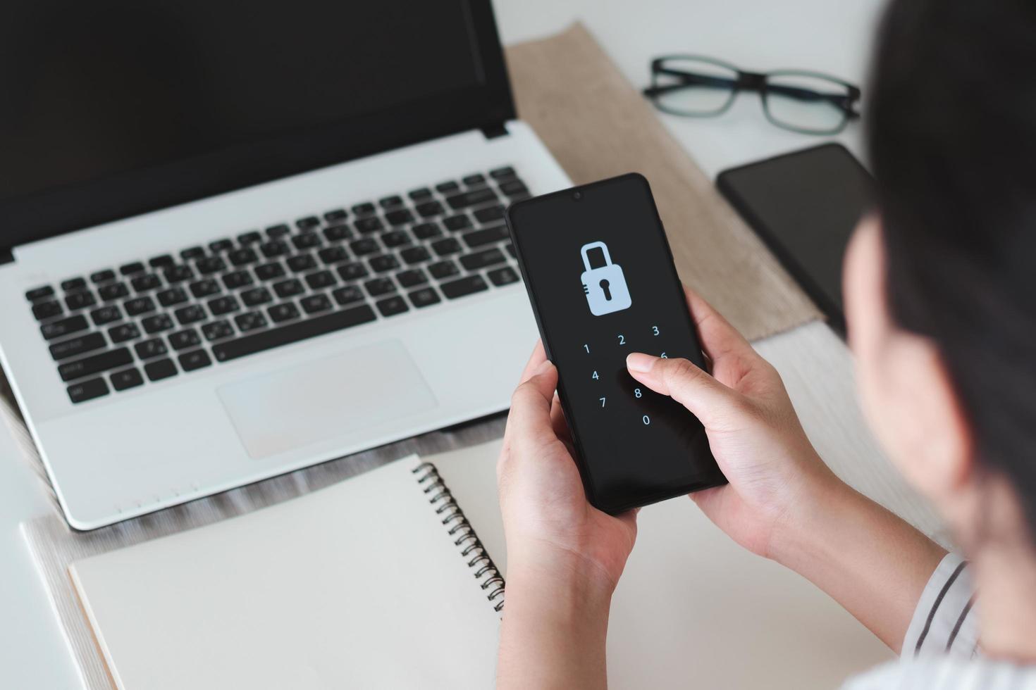 Hacking a Phishing mobile phone with a password to access a smartphone, security threats online, and fraud. A young man with a cell phone and laptop is secure in his bank account. photo