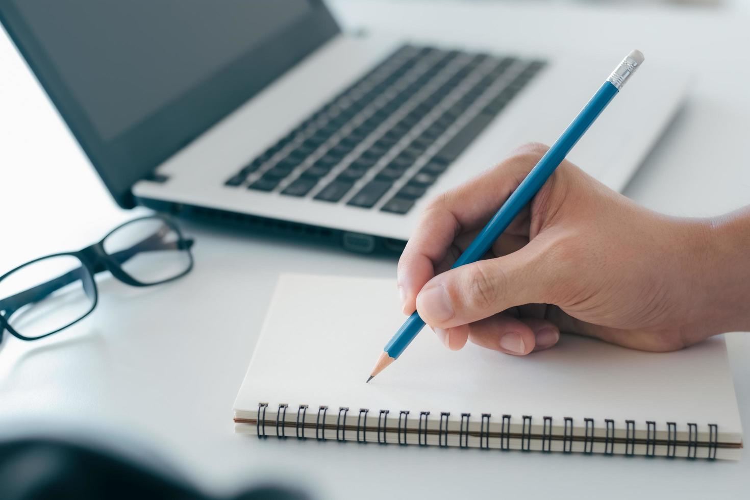 Businessman taking notes Summarize the meeting online with laptop, working alone, sitting at your desk. Working from home, close-up hands. photo