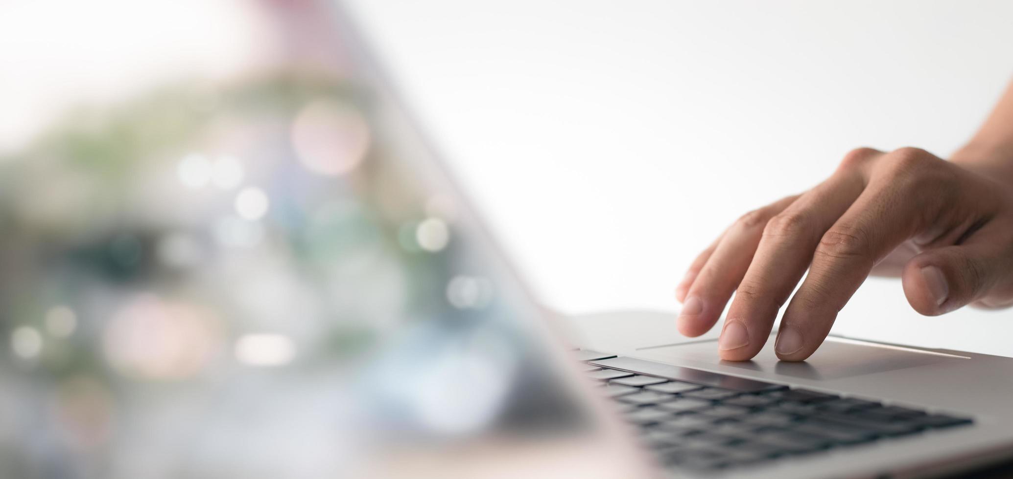 young man hand working on a laptop, bokeh blurred at natural For text copy space, image size horizontal. photo