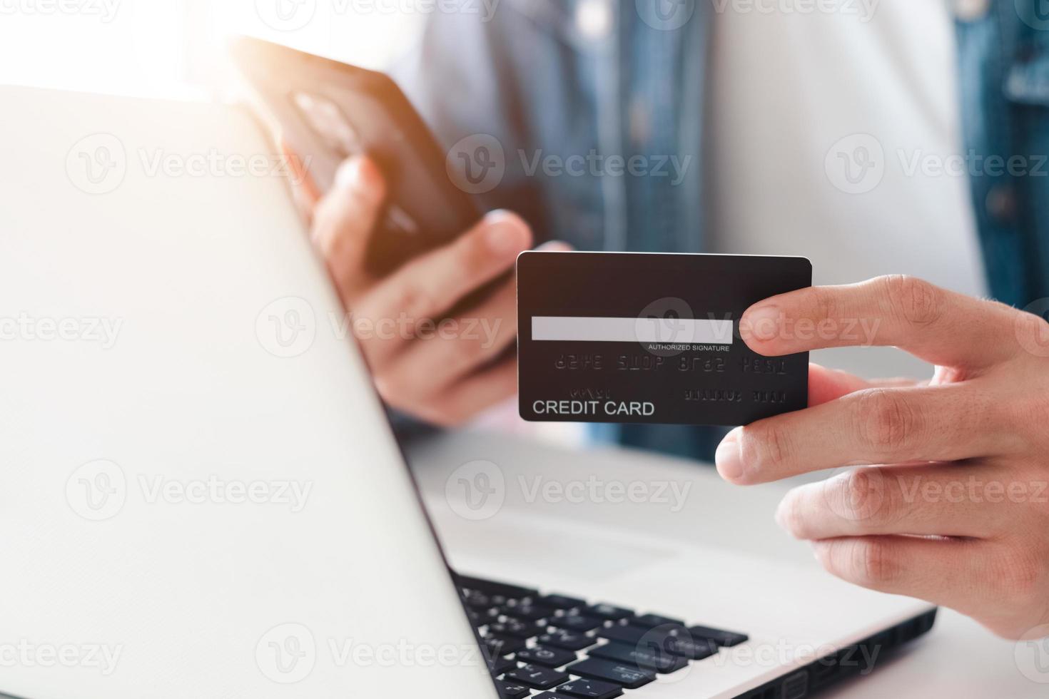 Businessman hand holding credit card with using laptop for online shopping while making orders at home. business, lifestyle, technology, ecommerce, digital banking and online payment concept. photo