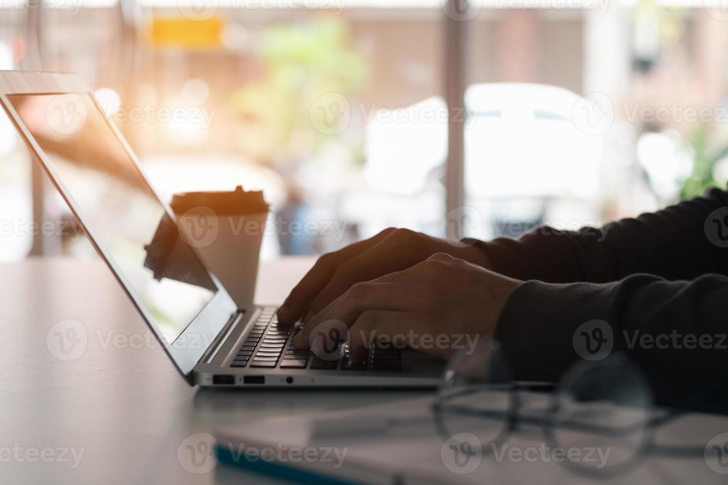 el hombre de negocios tomando notas resume la reunión en línea con una computadora portátil, trabajando solo, sentado en su escritorio. trabajando desde casa, manos de primer plano. foto