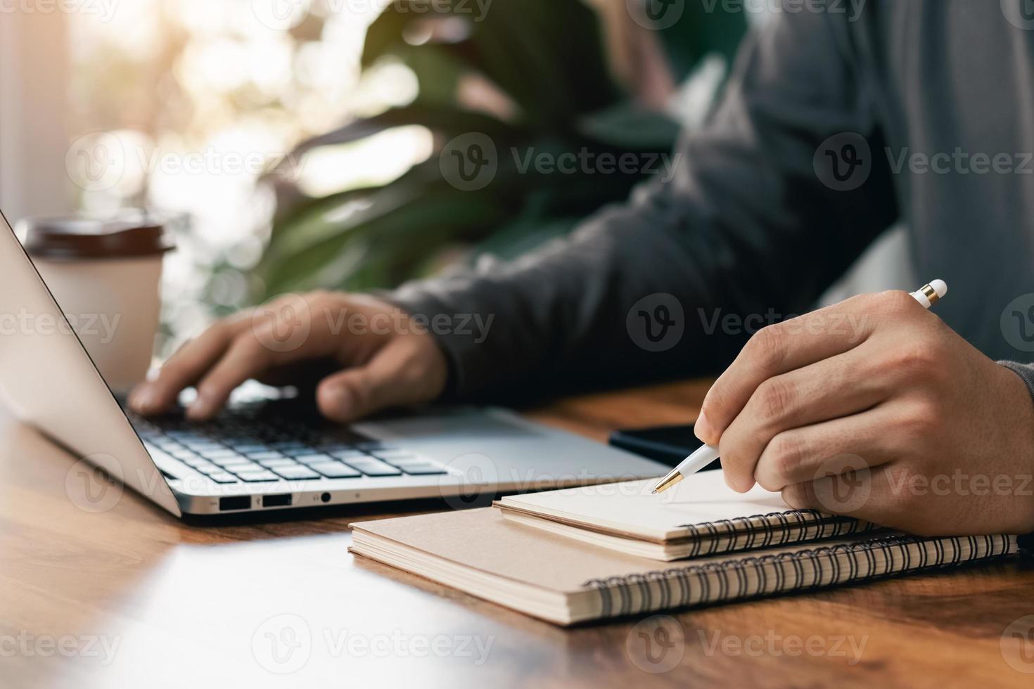 los hombres de negocios trabajan en computadoras y escriben en un bloc de notas con un bolígrafo para calcular los estados financieros dentro de la empresa. foto