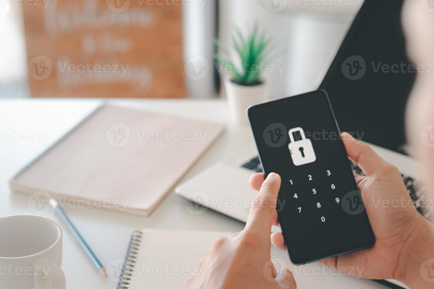 Hacking a Phishing mobile phone with a password to access a smartphone, security threats online, and fraud. A young man with a cell phone and laptop is secure in his bank account. photo