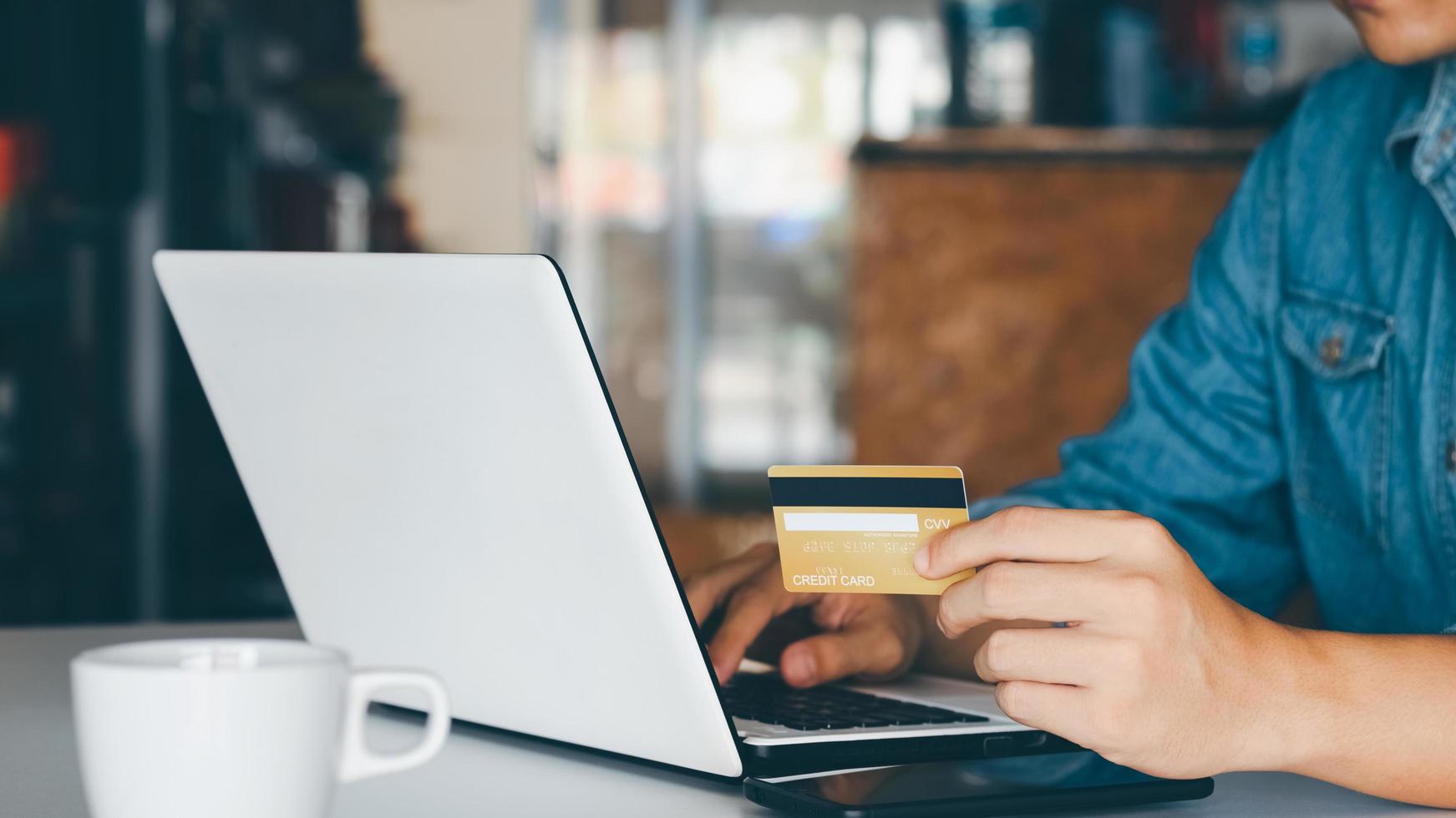 Businessman hand holding credit card with using laptop for online shopping while making orders at home. business, lifestyle, technology, ecommerce, digital banking and online payment concept. photo