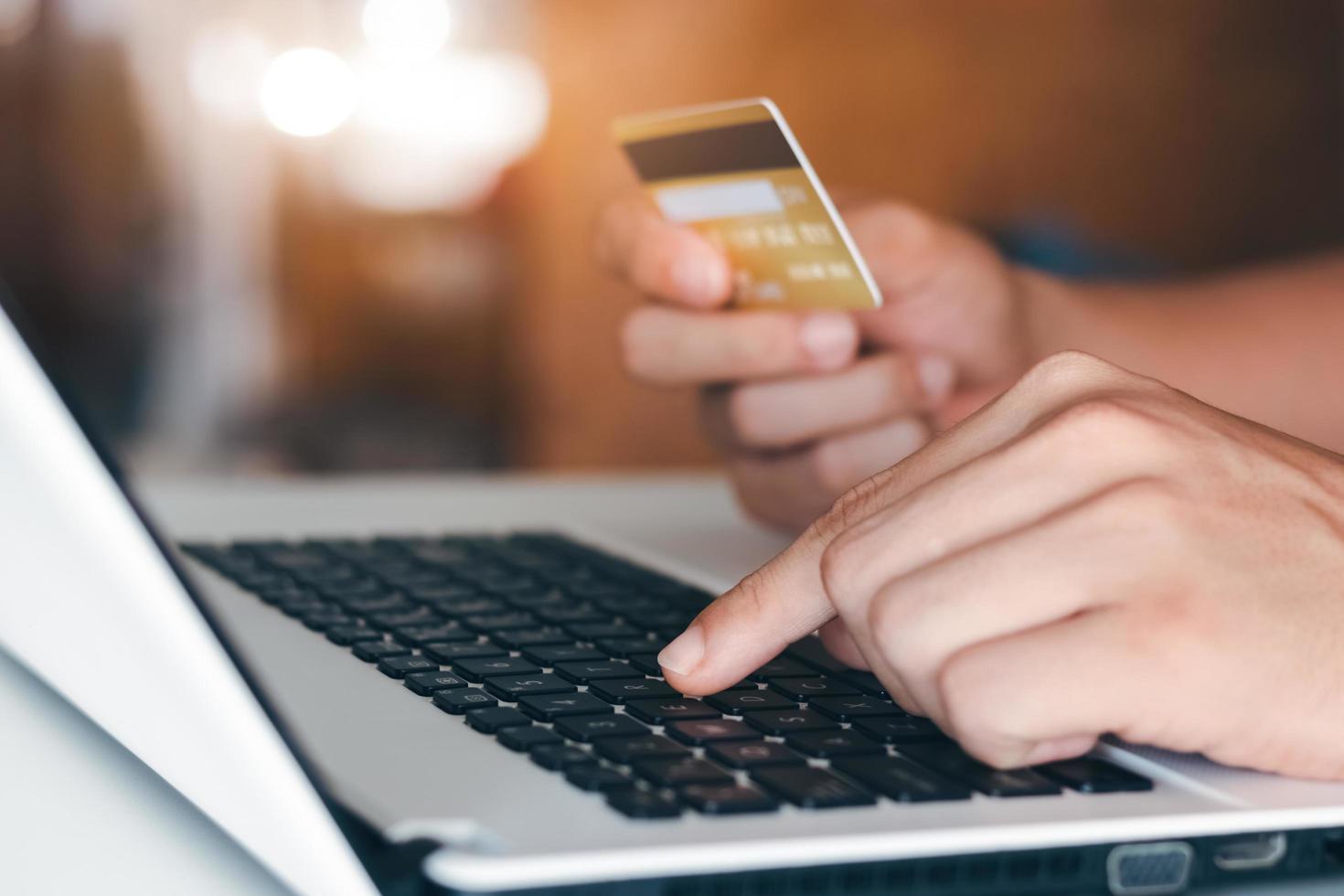 Businessman hand holding credit card with using laptop for online shopping while making orders at home. business, lifestyle, technology, ecommerce, digital banking and online payment concept. photo