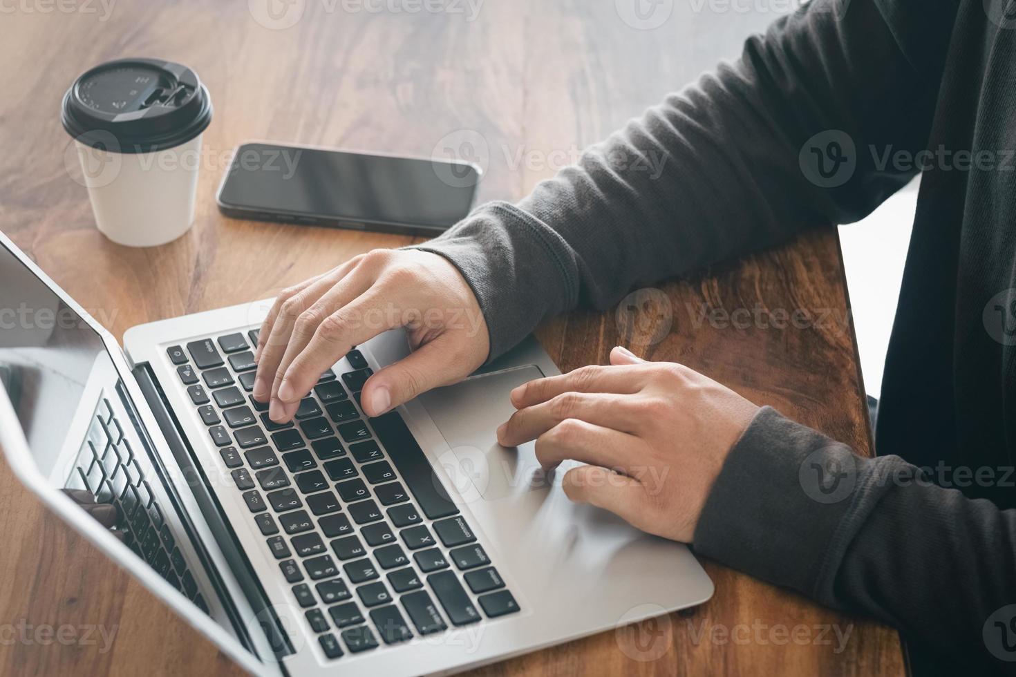 el hombre de negocios tomando notas resume la reunión en línea con una computadora portátil, trabajando solo, sentado en su escritorio. trabajando desde casa, manos de primer plano. foto