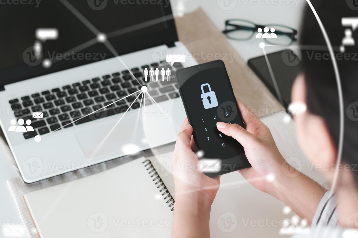 Hacking a Phishing mobile phone with a password to access a smartphone, security threats online, and fraud. A young man with a cell phone and laptop is secure in his bank account. photo