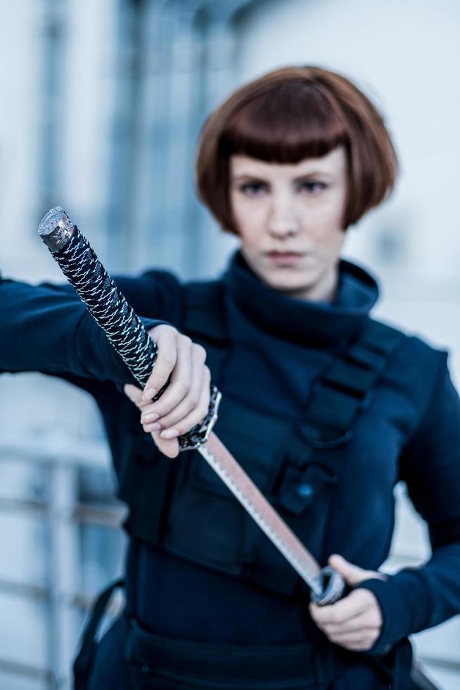 portrait of young redhead woman with japanese sword dressed in futuristic cyberpunk costume standing on the roof. photo